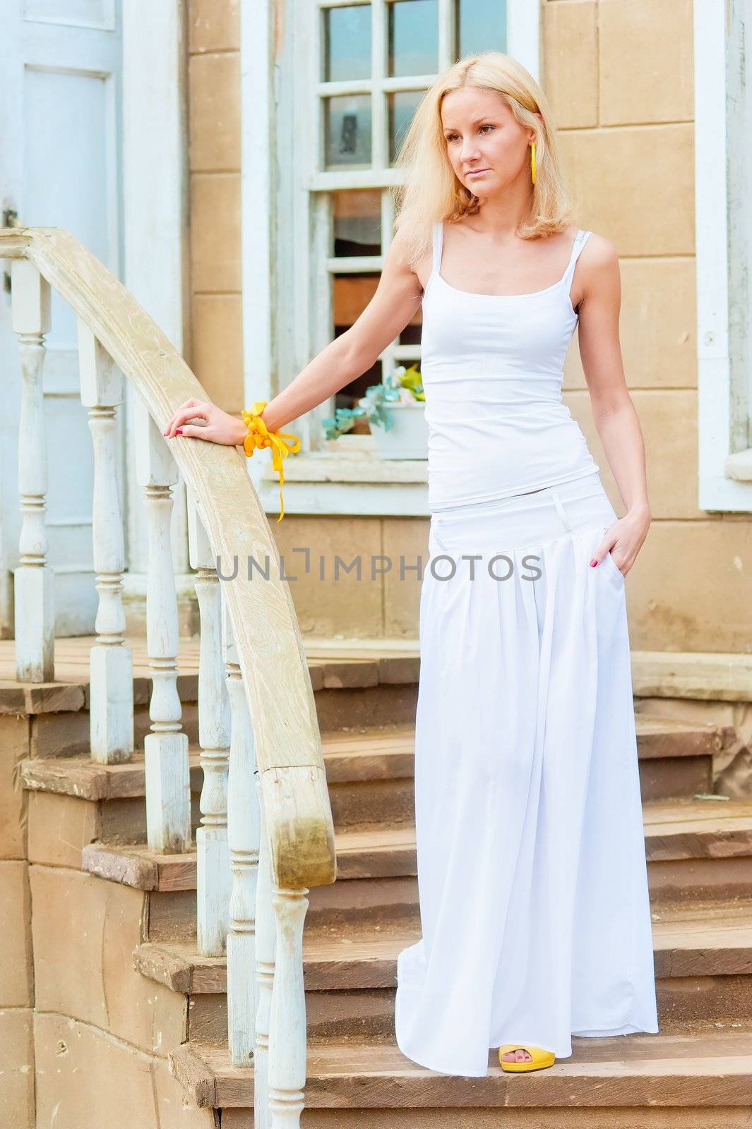 Young slim girl on the front stairs of the old mansion.