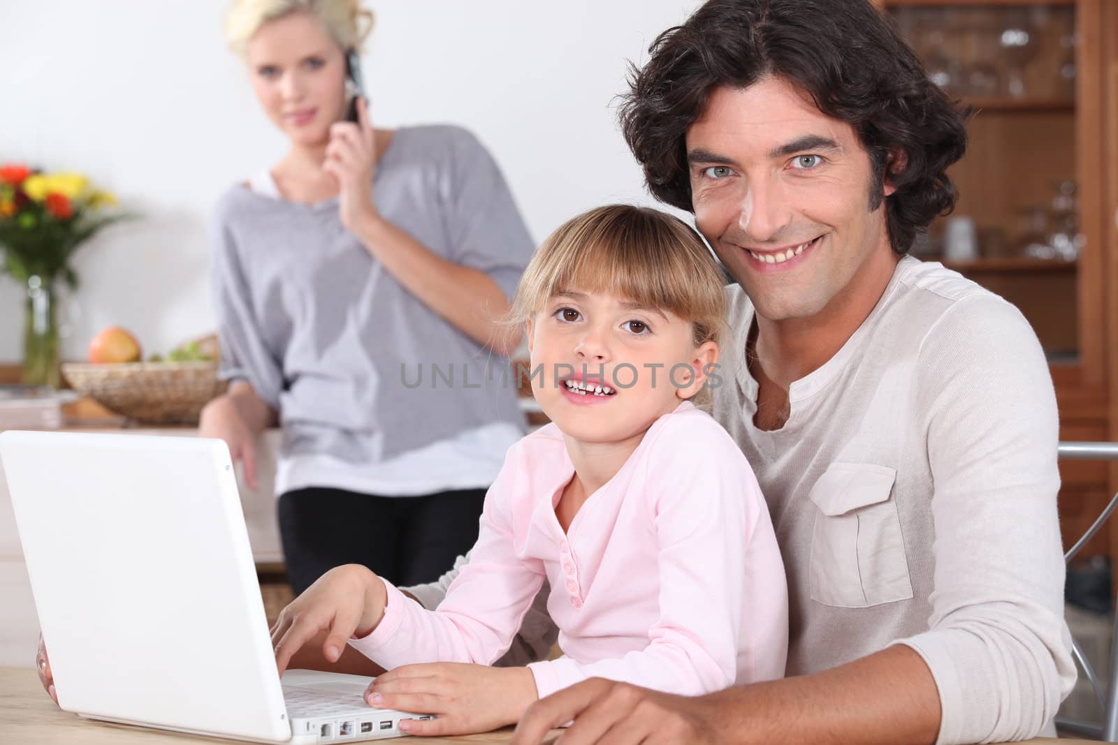 Parents and little girl with laptop by phovoir