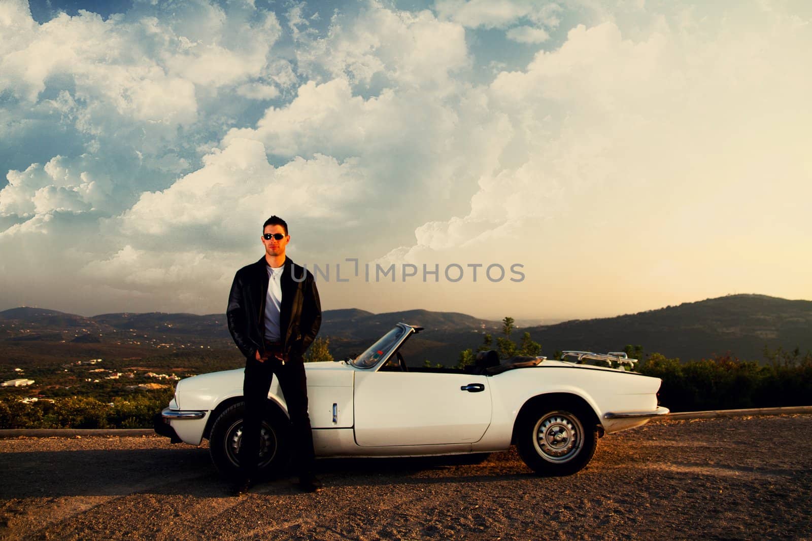 View of a young male with a jacket next to his white convertible car.