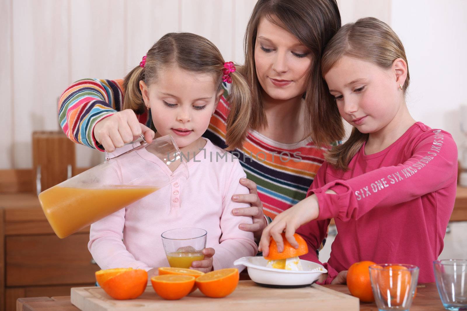 Family squeezing fresh orange juice by phovoir