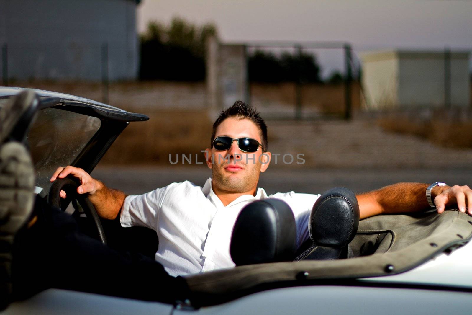 View of a young male next to his white convertible car.