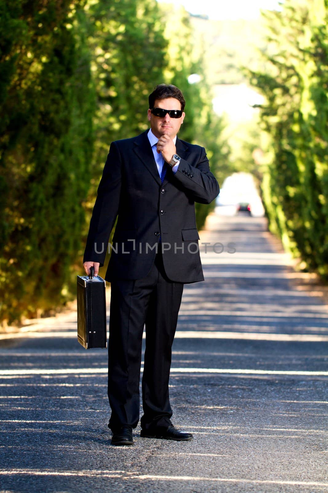 View of a young male business man on a asphalt road.