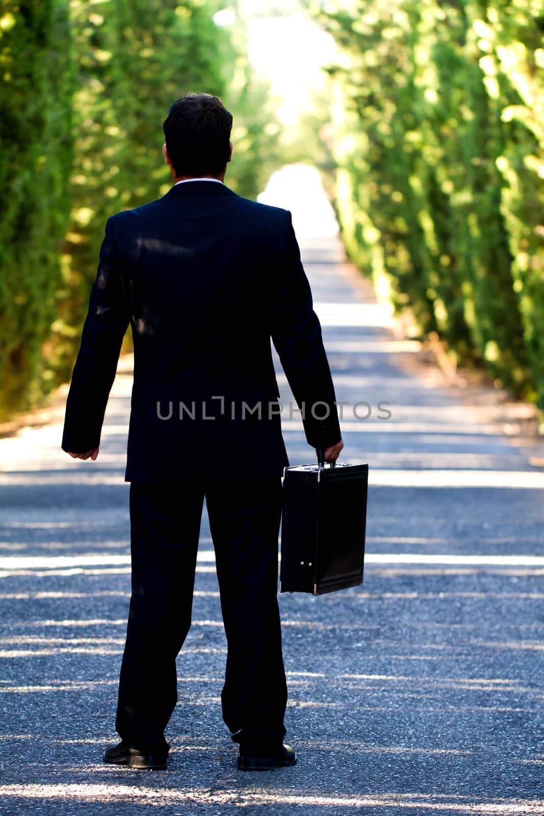 View of a young male business man on a asphalt road.