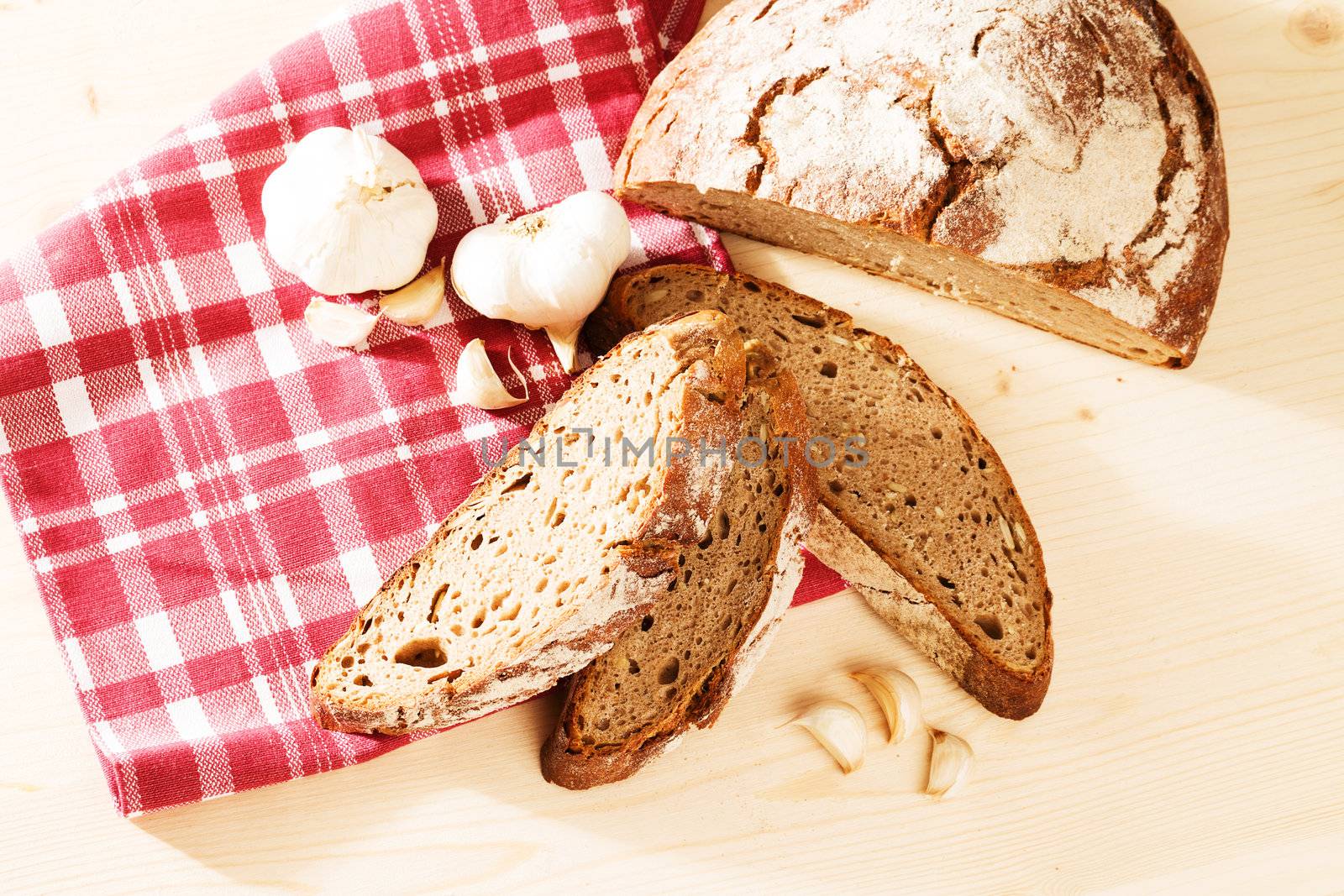 rustic rye bread from top with garlic on wooden background with a towel