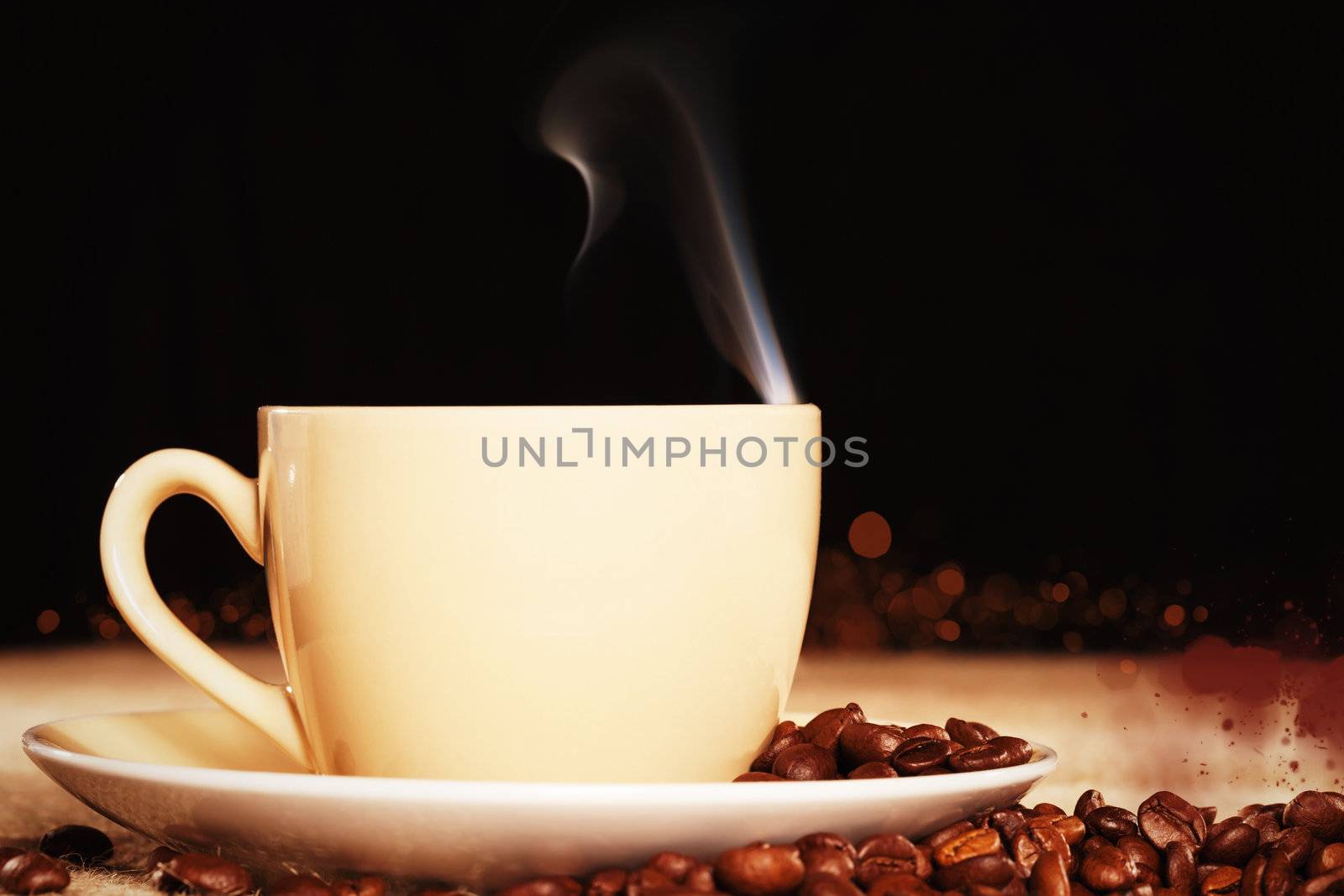 steaming coffee cup with coffee beans on a jute fabric with black background