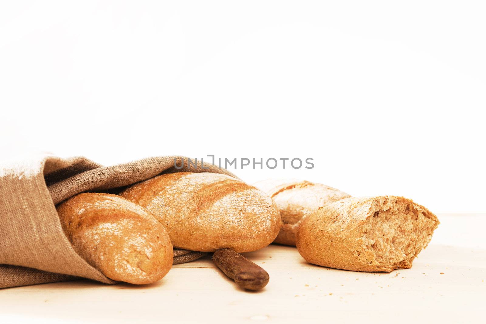 rustic rye buns with a linen fabric and a old knife on wooden background