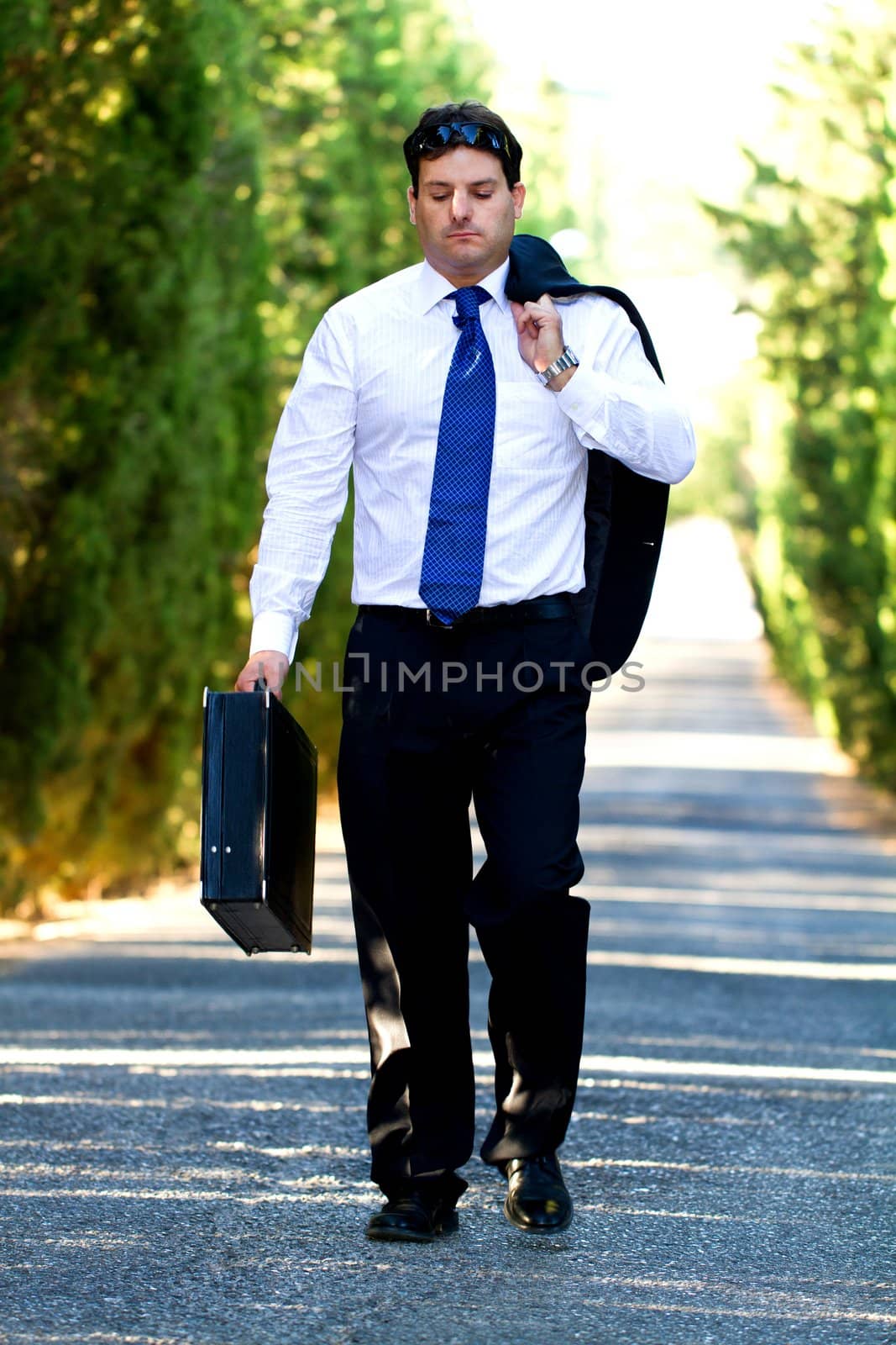 View of a young male business man on a asphalt road.