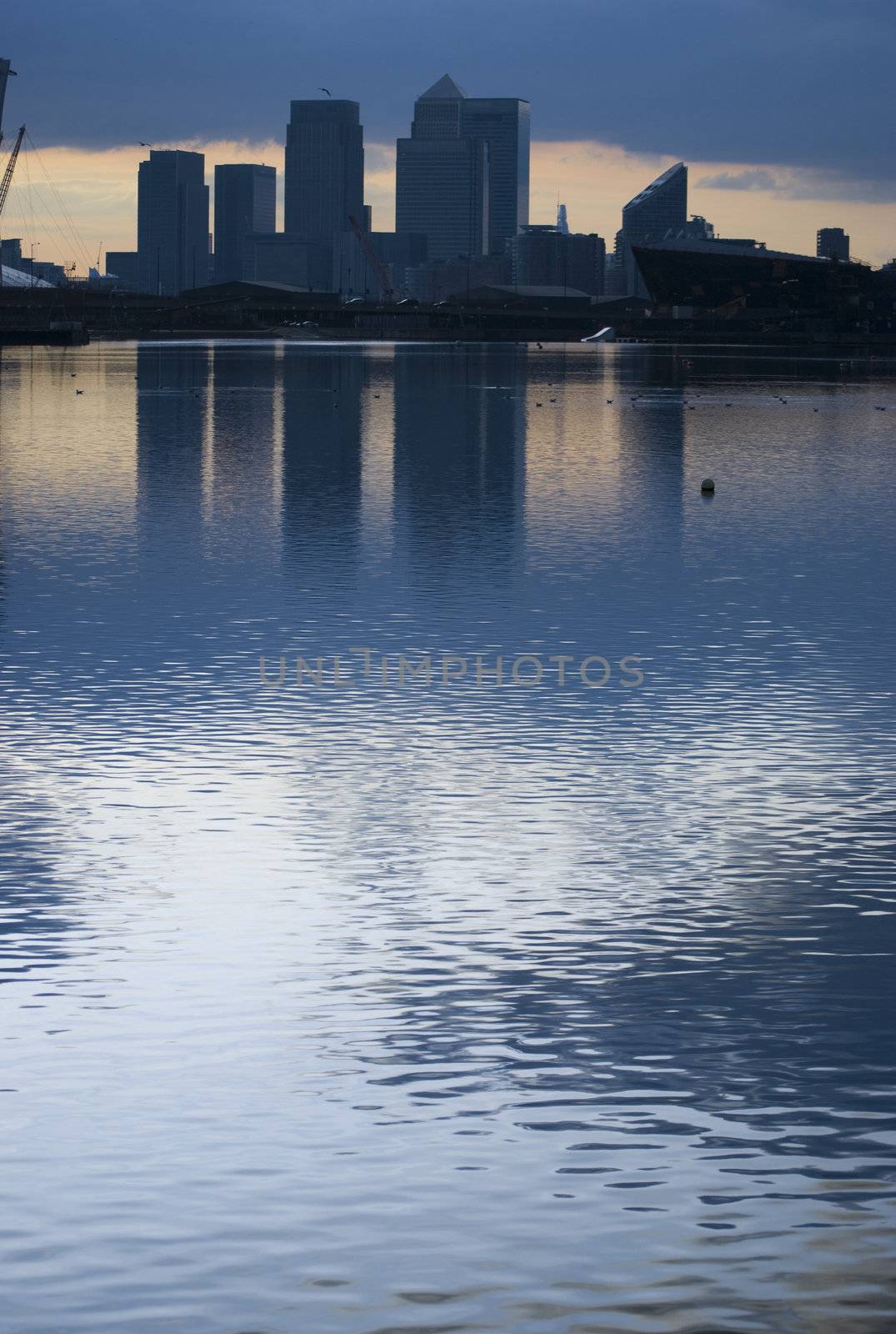 blue tone of canary wharf silhouette over canal at sunset