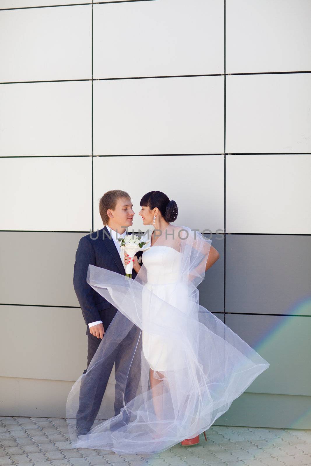 bride and groom by the wall