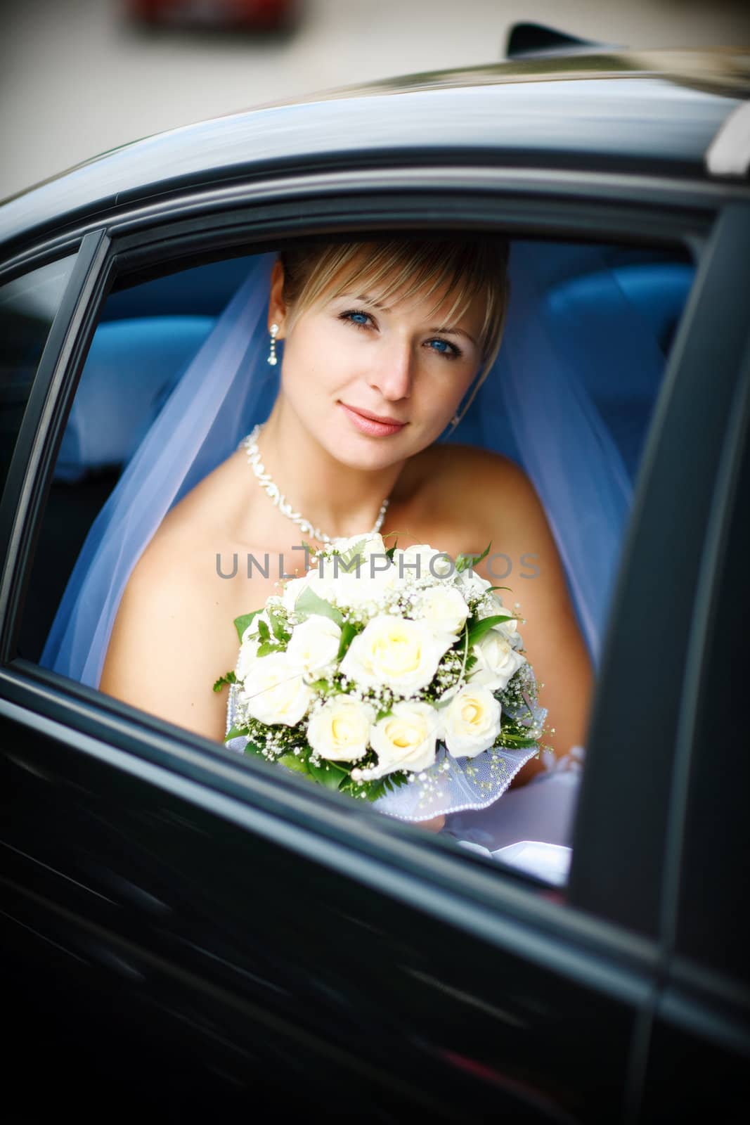 happy bride with flower bouquet siting in the car
