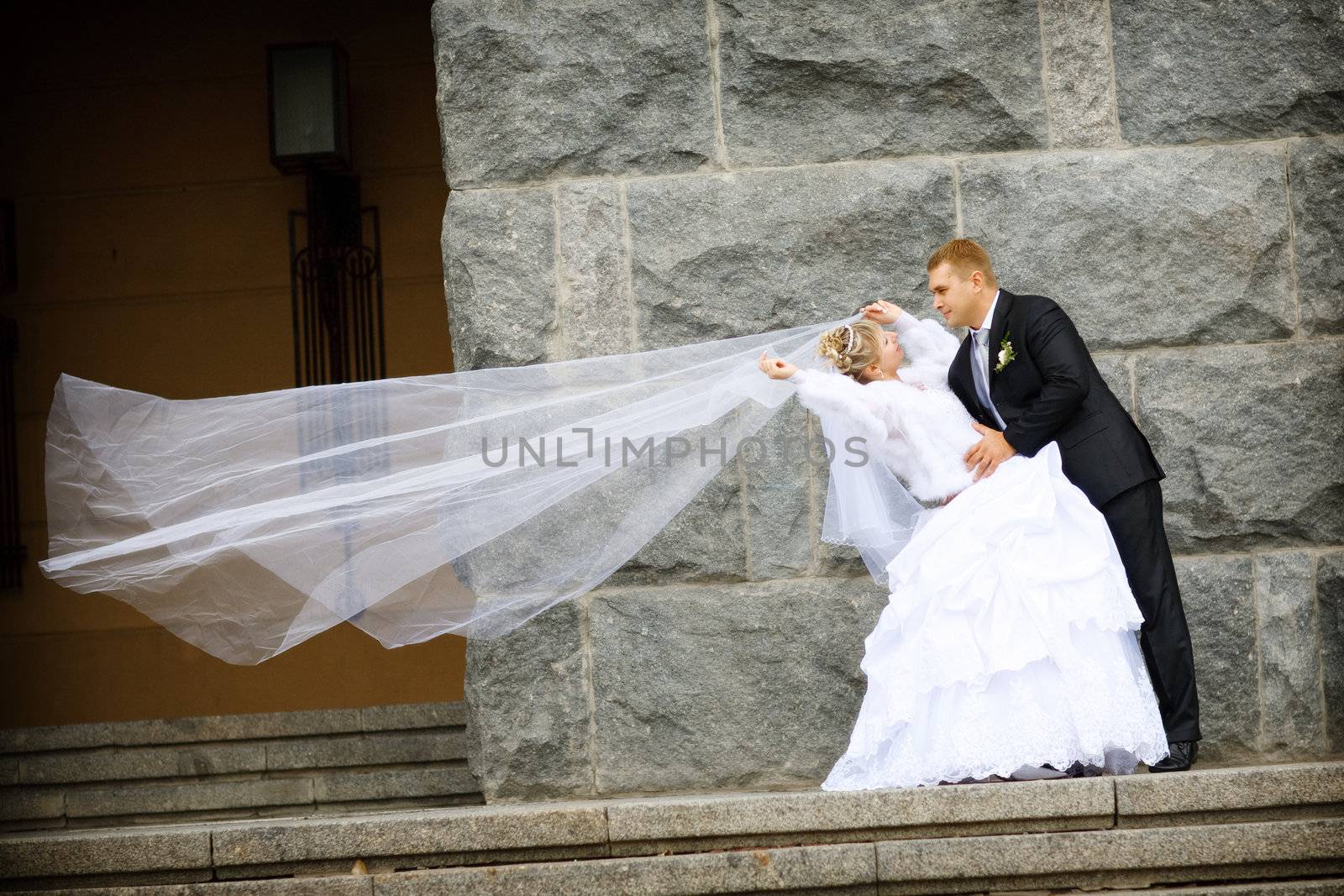 bride and groom kissing near the wall