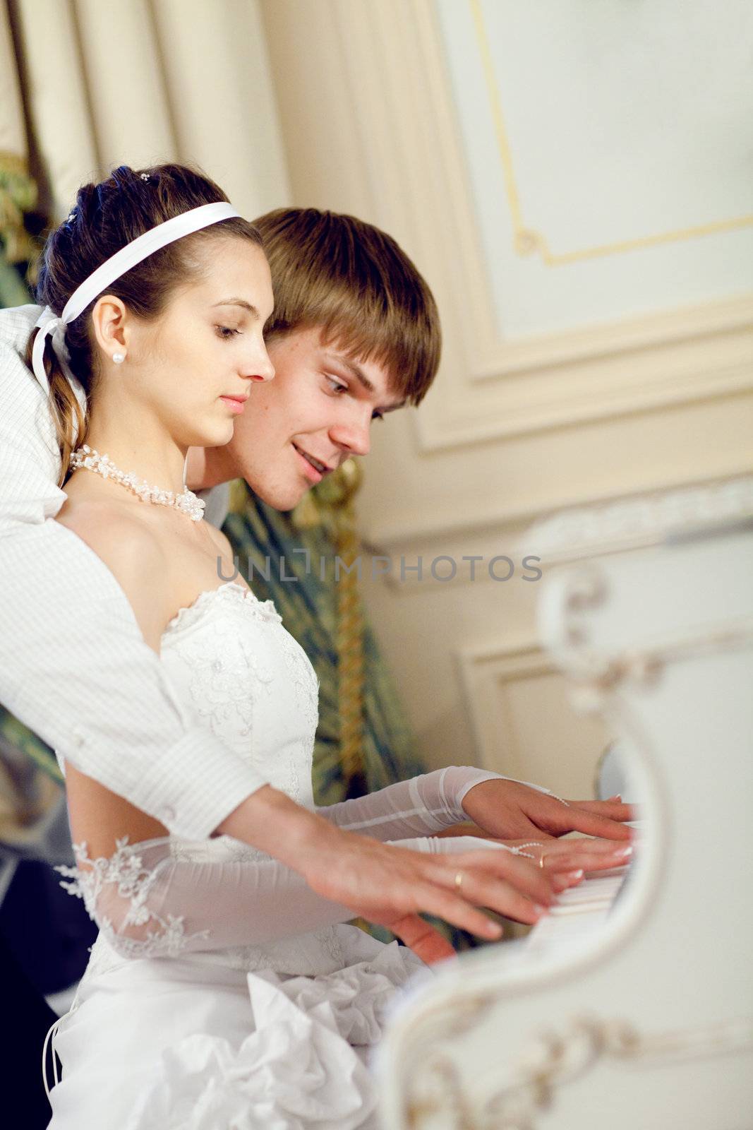 man teaching his bride to play the piano
