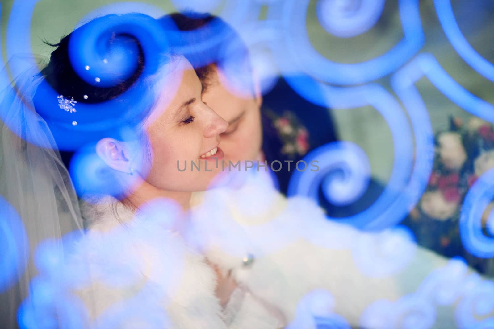 bride with closed eyes and groom through the ornate glass