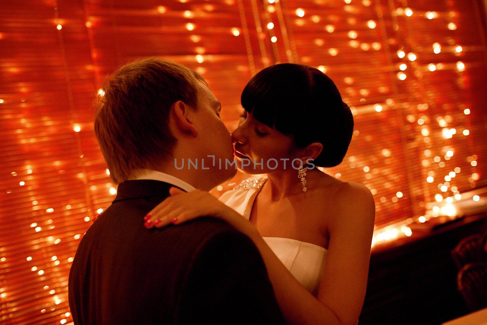 kissing couple by the window with lights