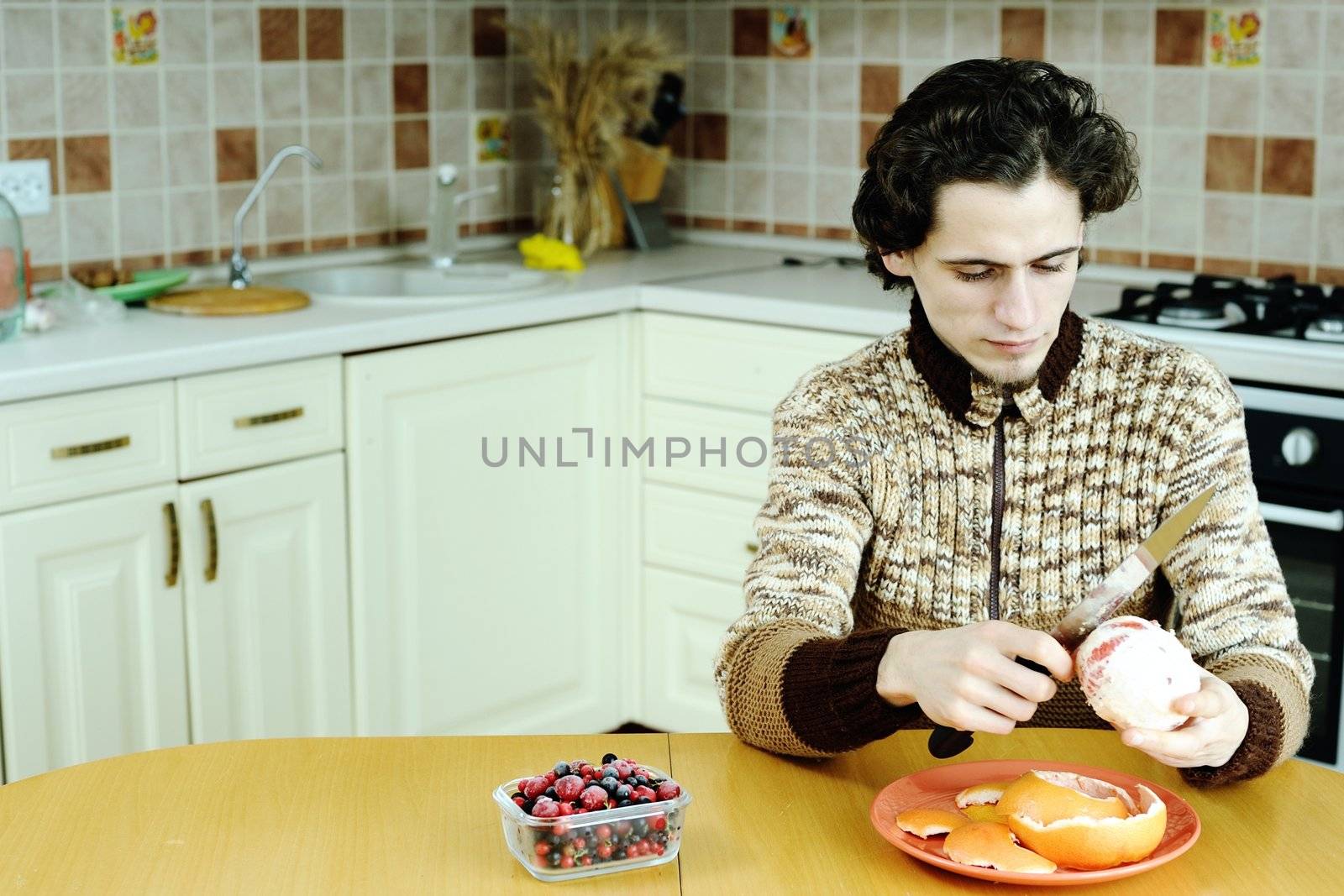 A man peelling the grapefruit in the kitchen