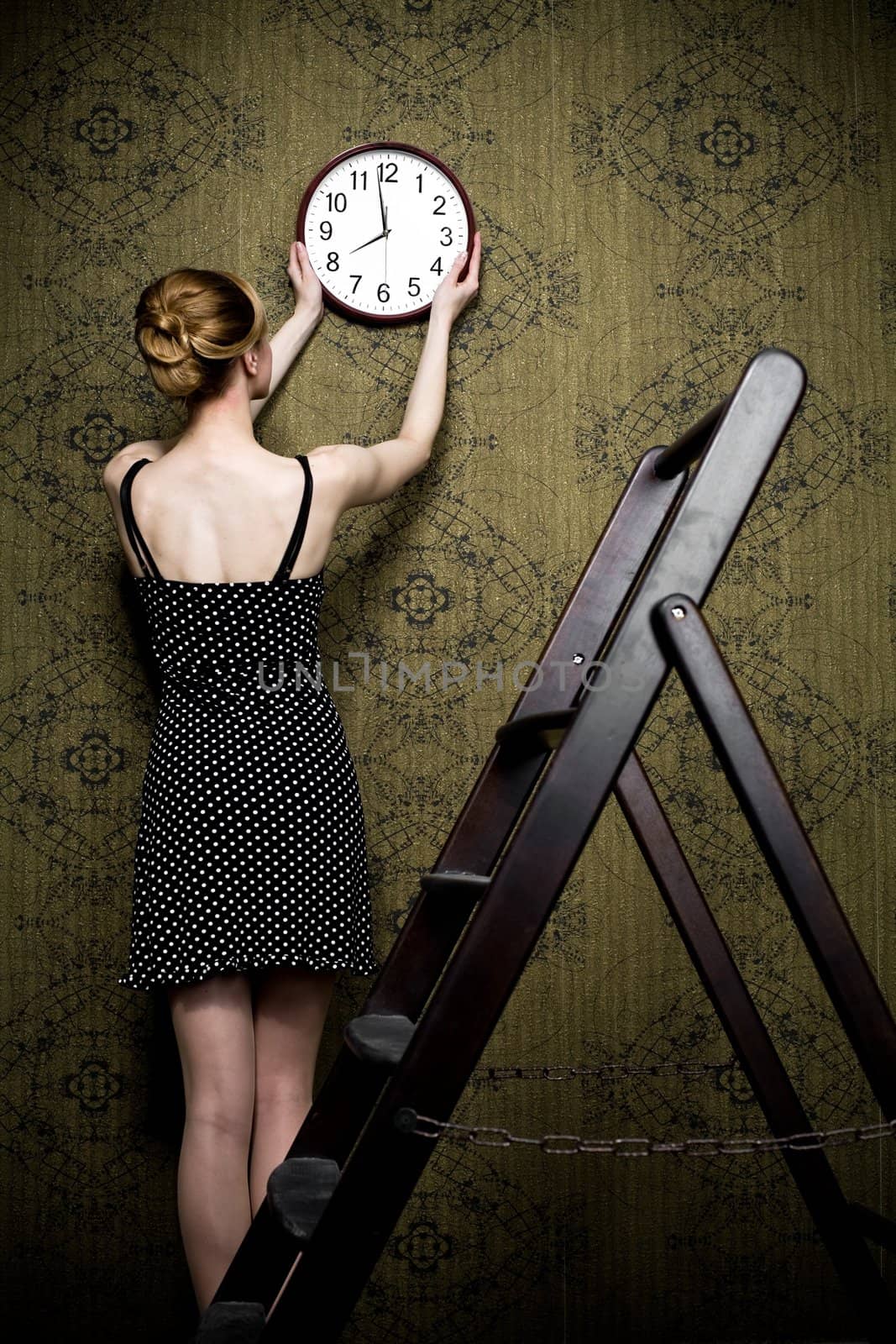 An image of a woman hanging a clock on the wall