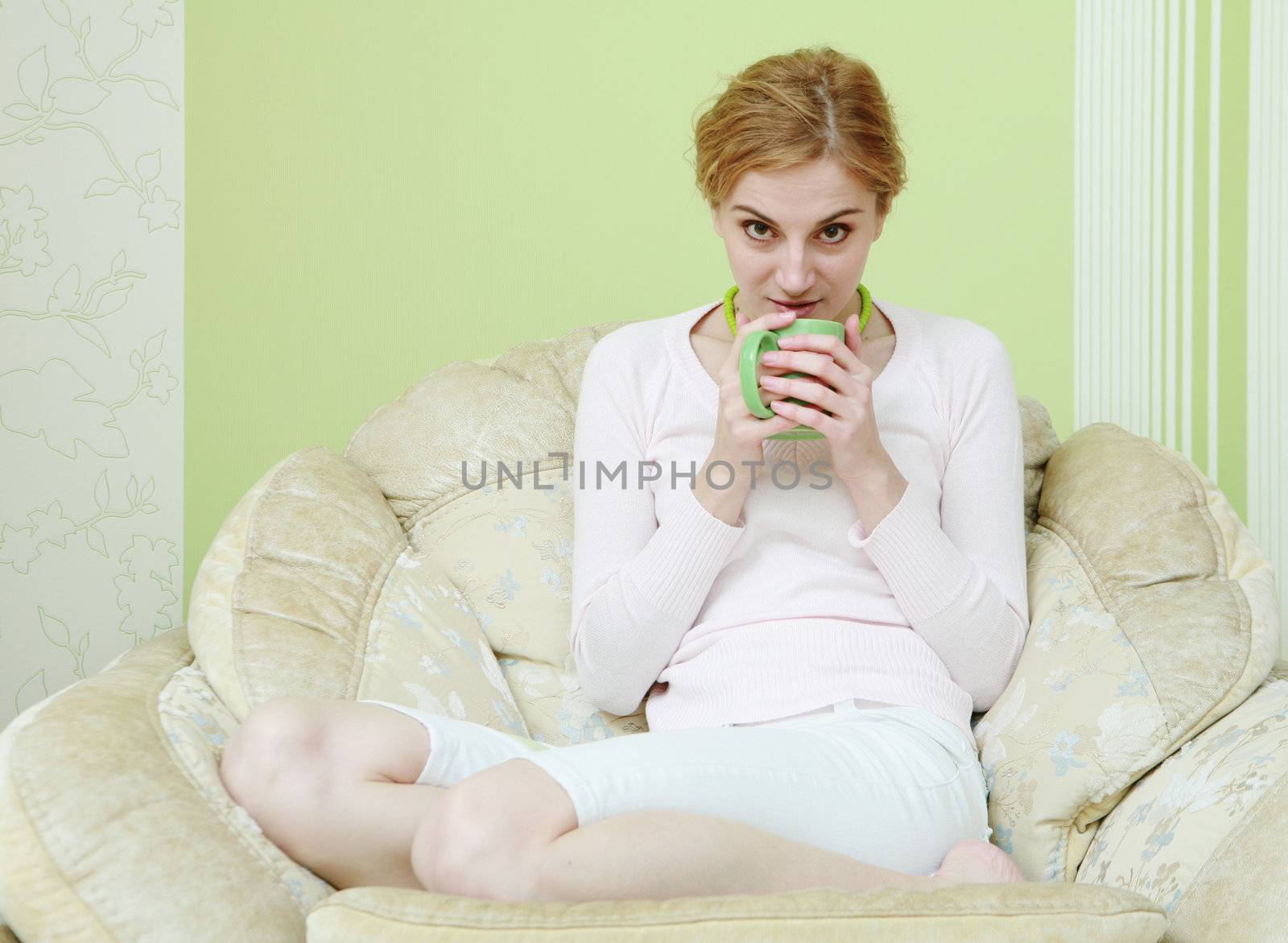 A woman drinking tea in the armchair