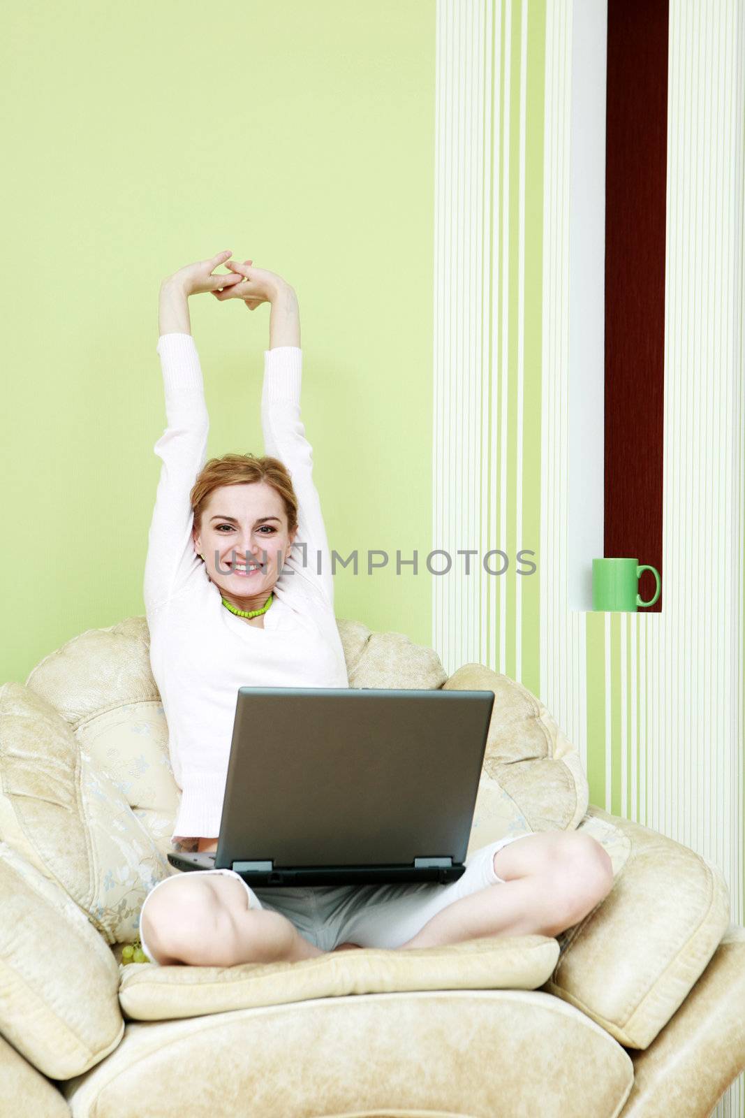 An image of a woman with laptop in armchair
