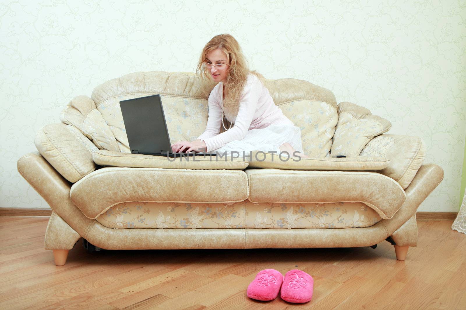 An image of a girl with a laptop on a sofa