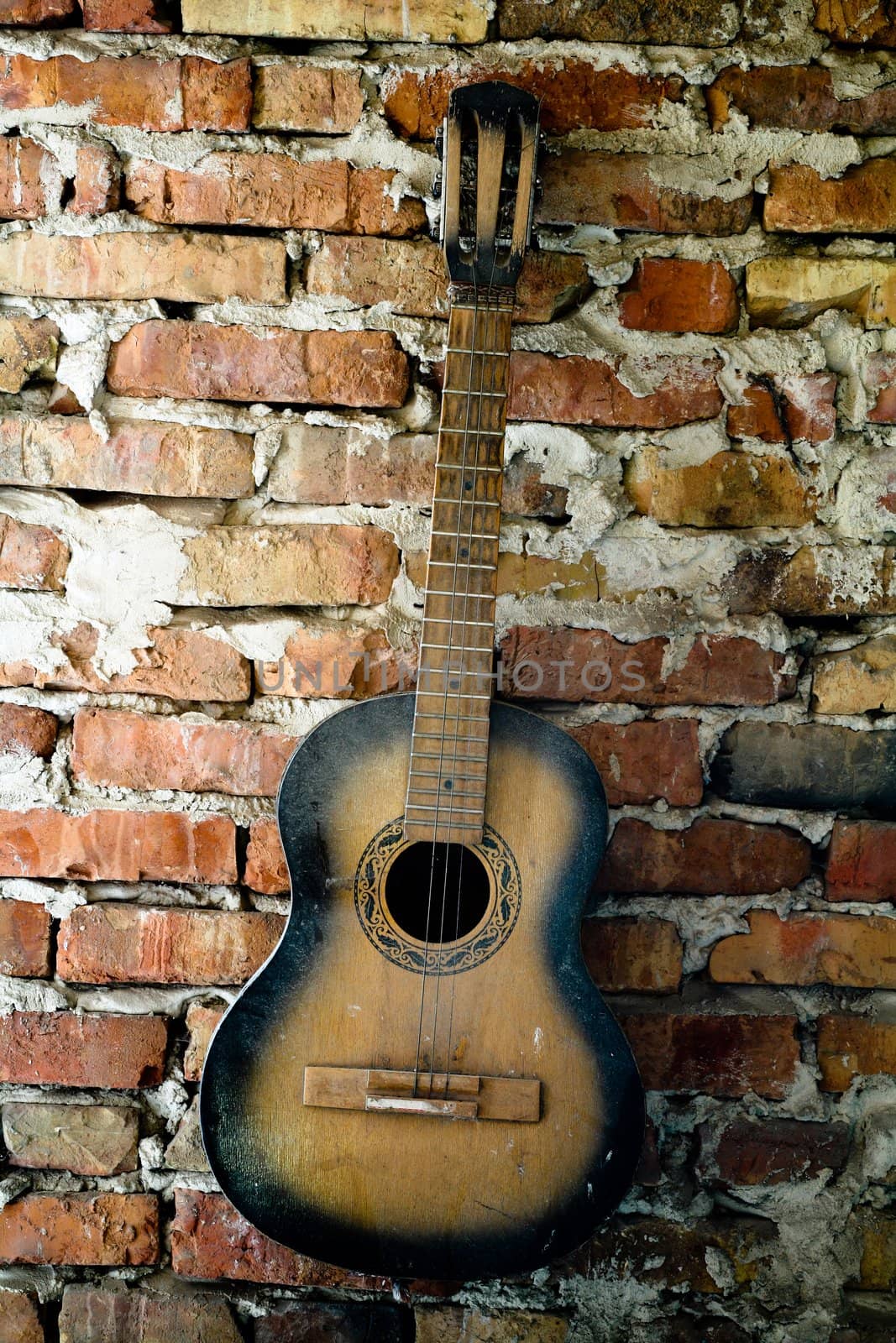 an old guitar on the brick wall