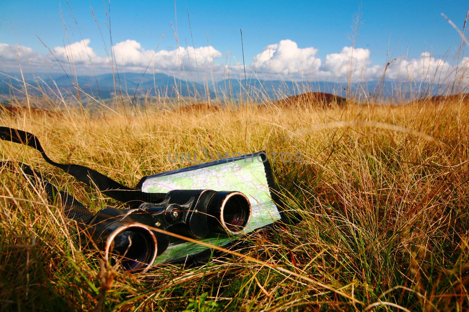 An image of binoculars and map on grass