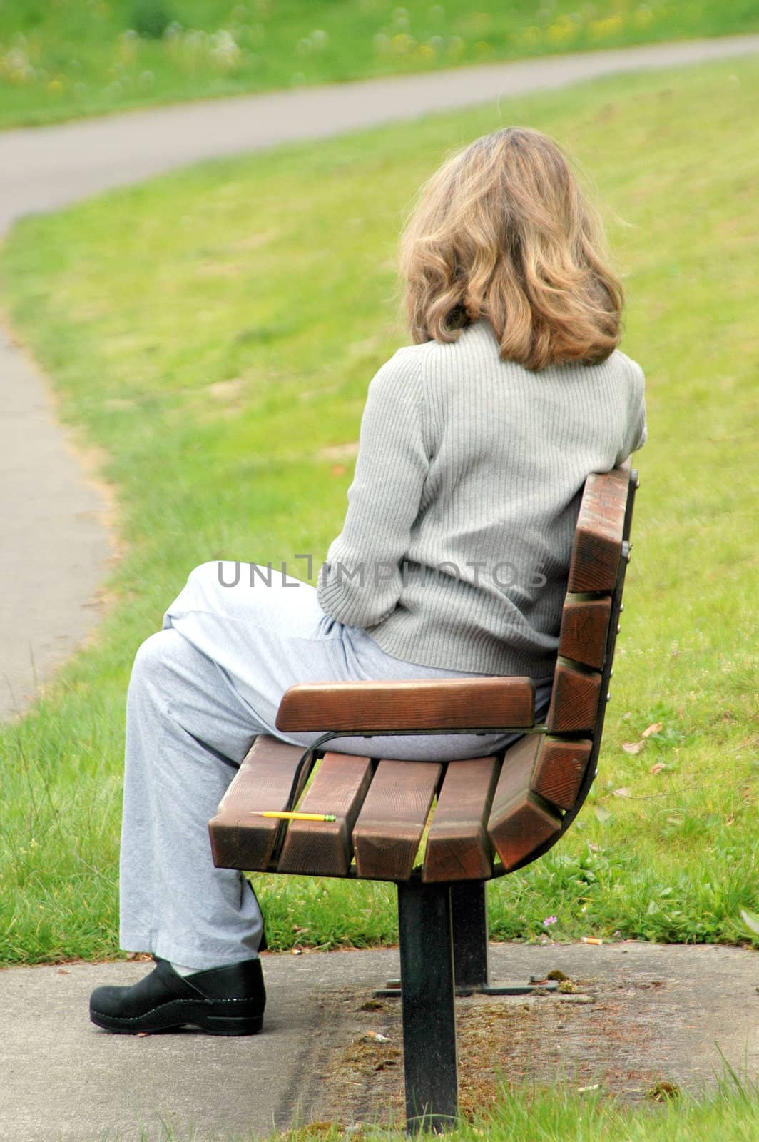 Female relaxing on park bench outside.