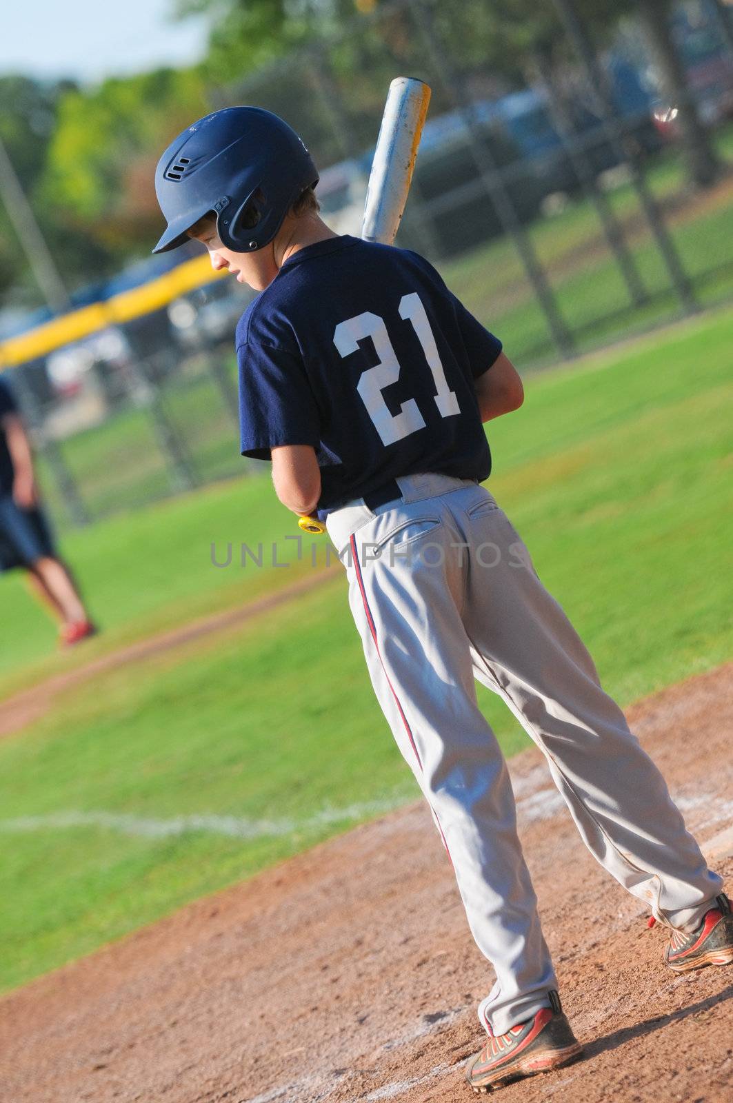 Youth baseball player waiting to bat at home plate.