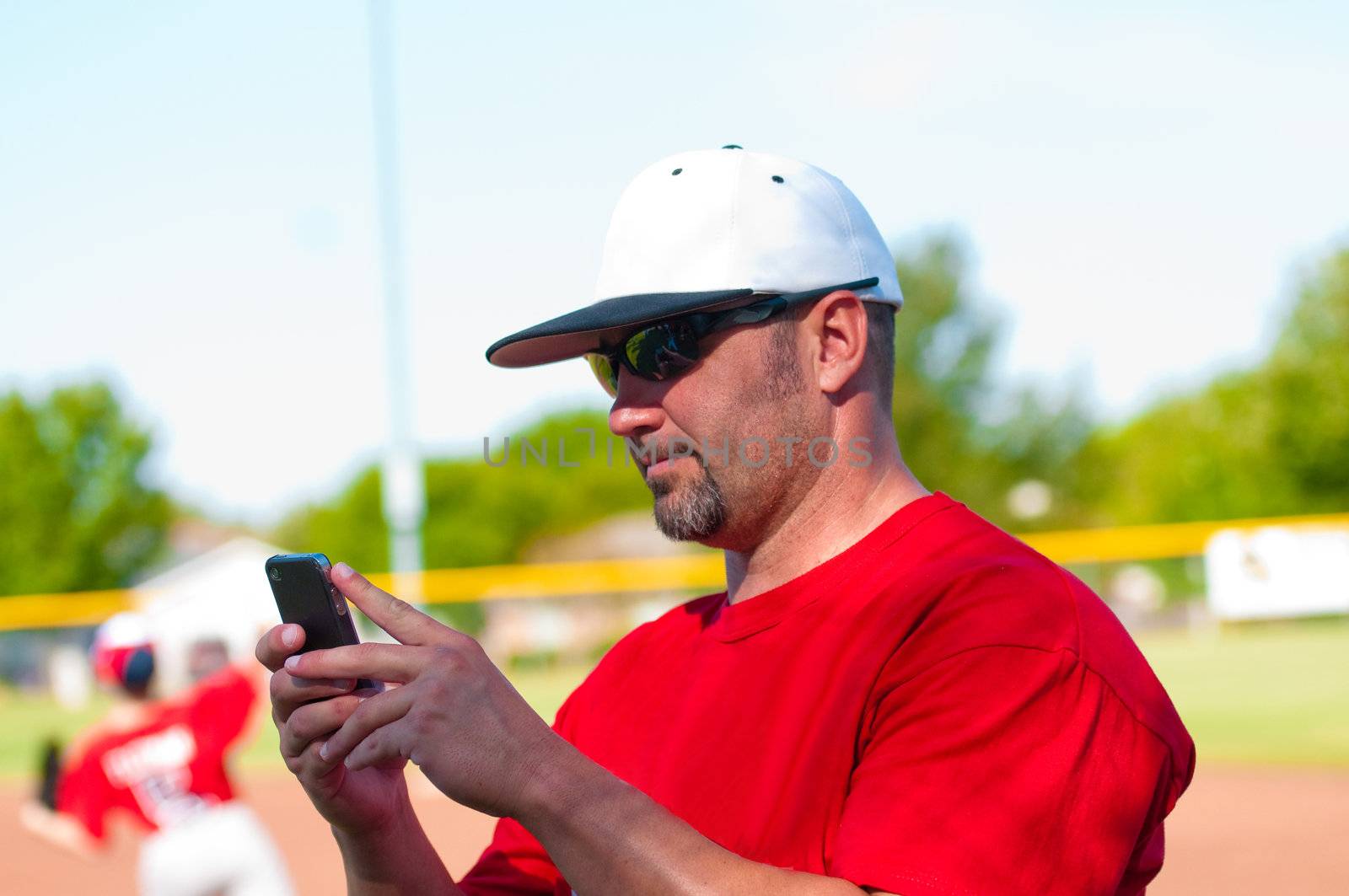 Baseball coach on cell phone during the game.