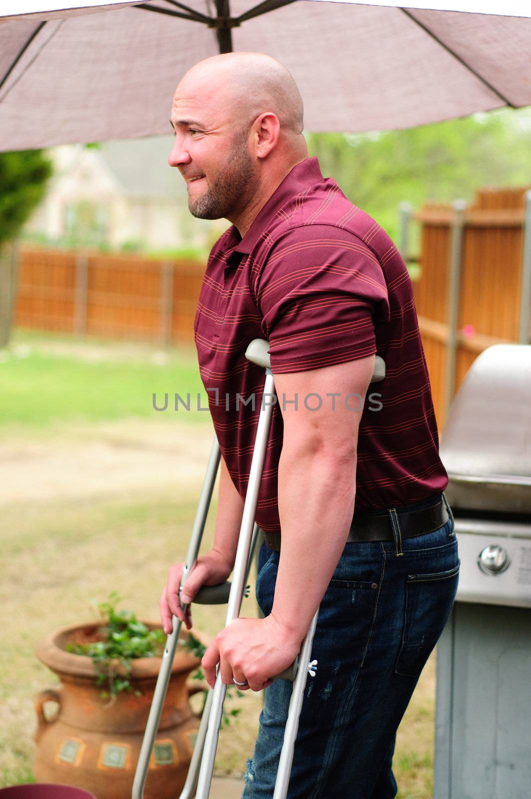 Muscular bald man on crutches outdoor.