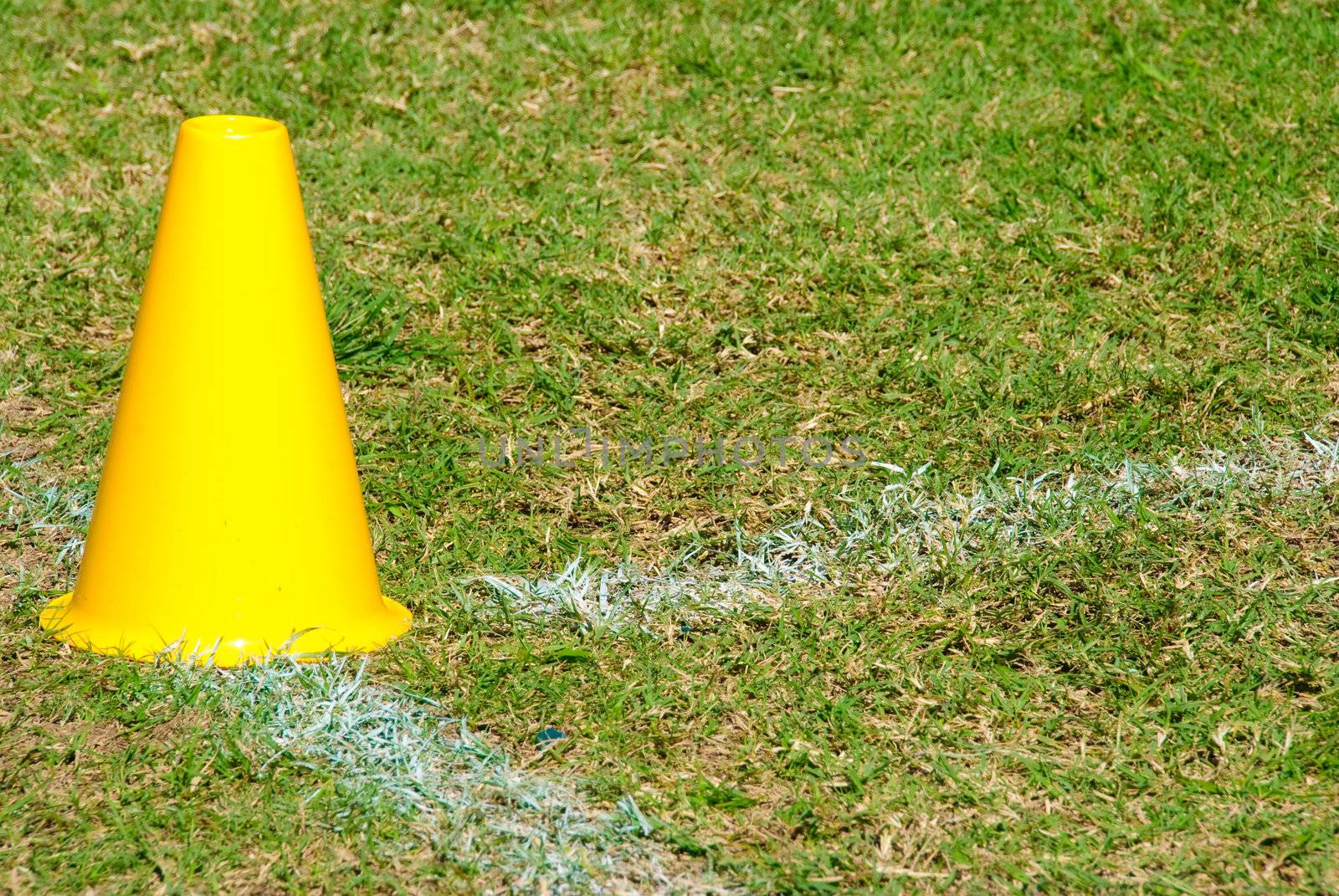 Yellow cone on a grass football field.