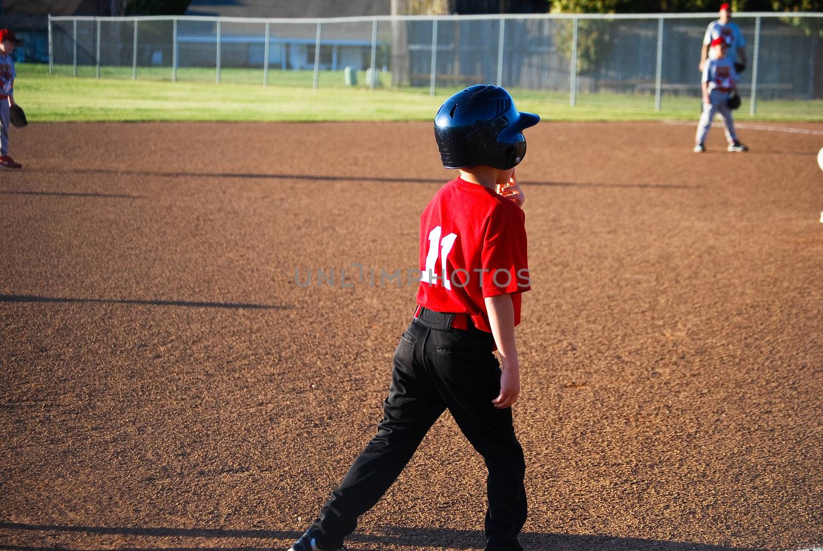 Youth baseball player on third base getting ready to run.