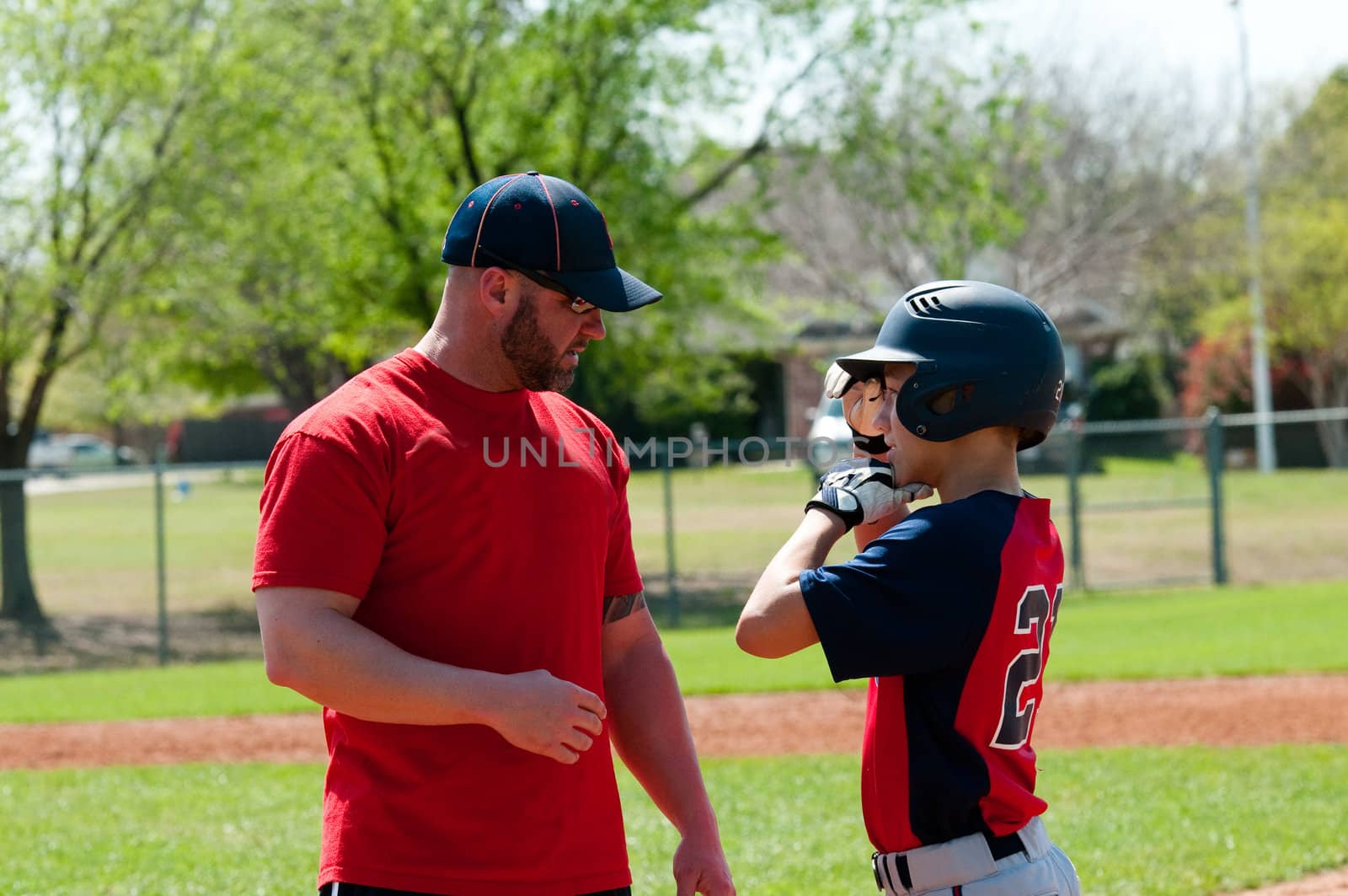 Baseball coach giving instruction to teen baseball boy.
