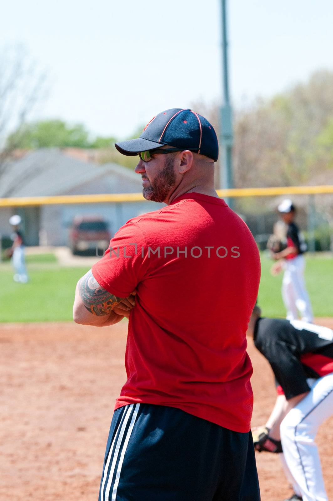 Baseball coach at first base line looking at batter.