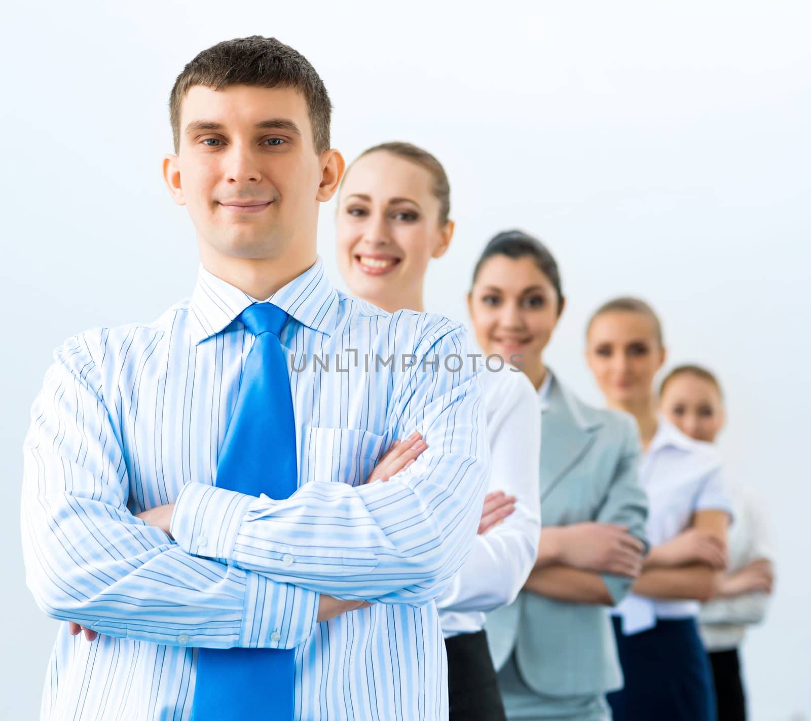 group of business people standing in a row, smiling and crossing his arms