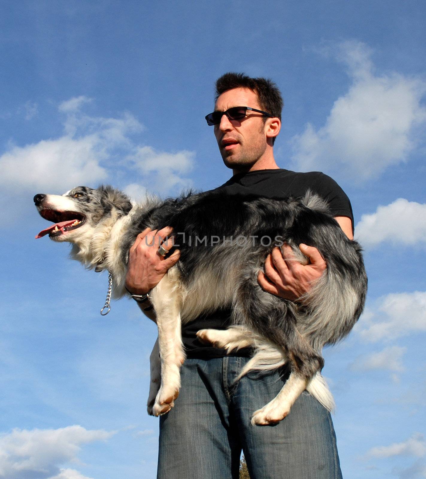 a man carrying his purebred border collie in the nature