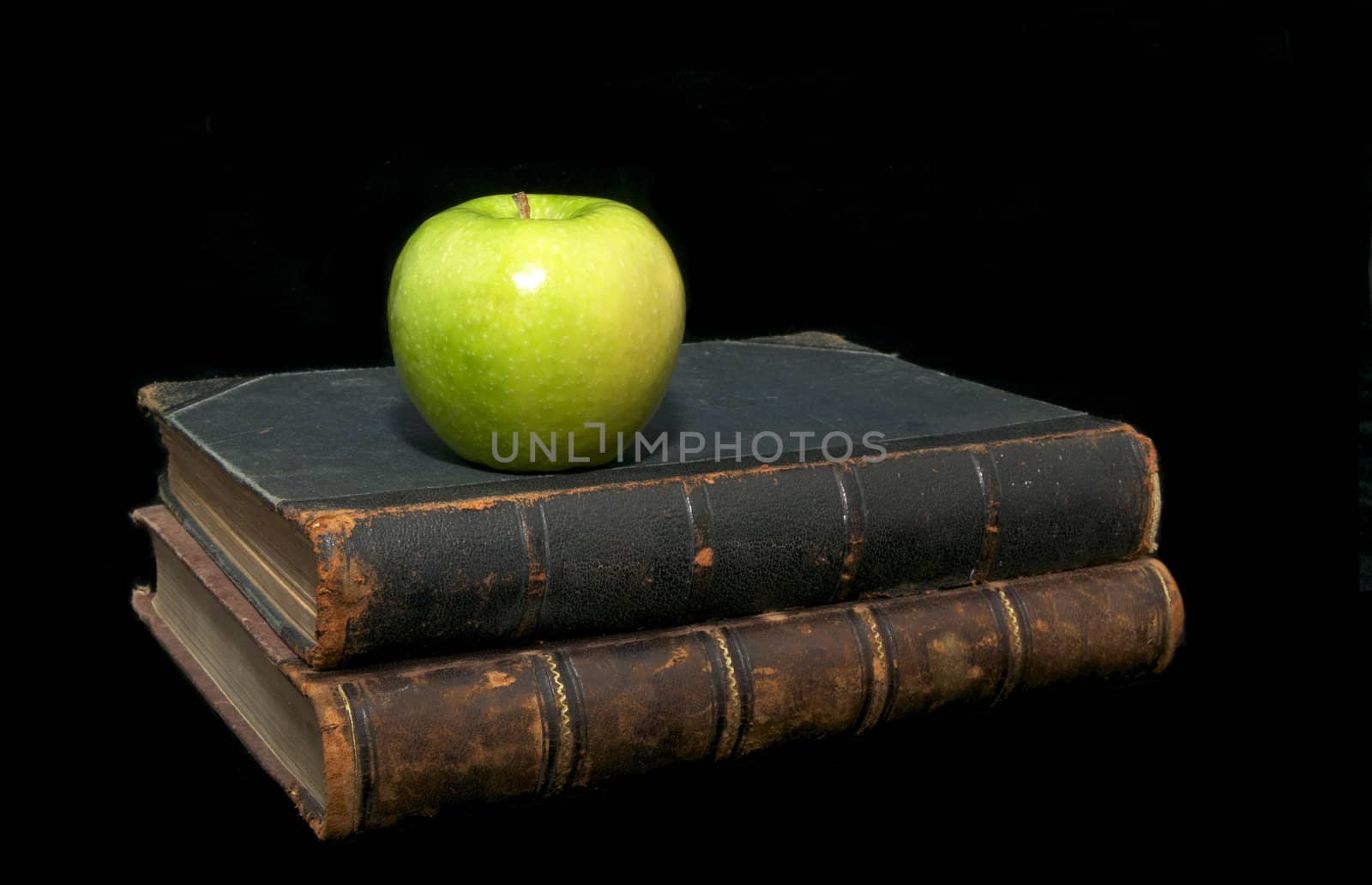 old books and an apple on a black background