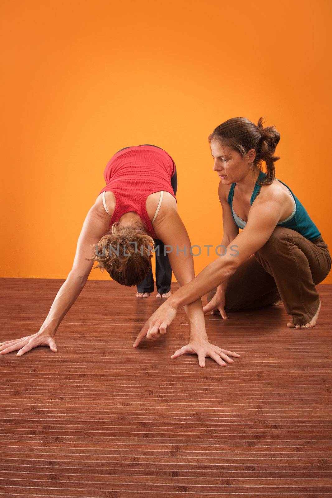 Yogasana teacher assisting her student with the Adho Mukha Svanasana posture