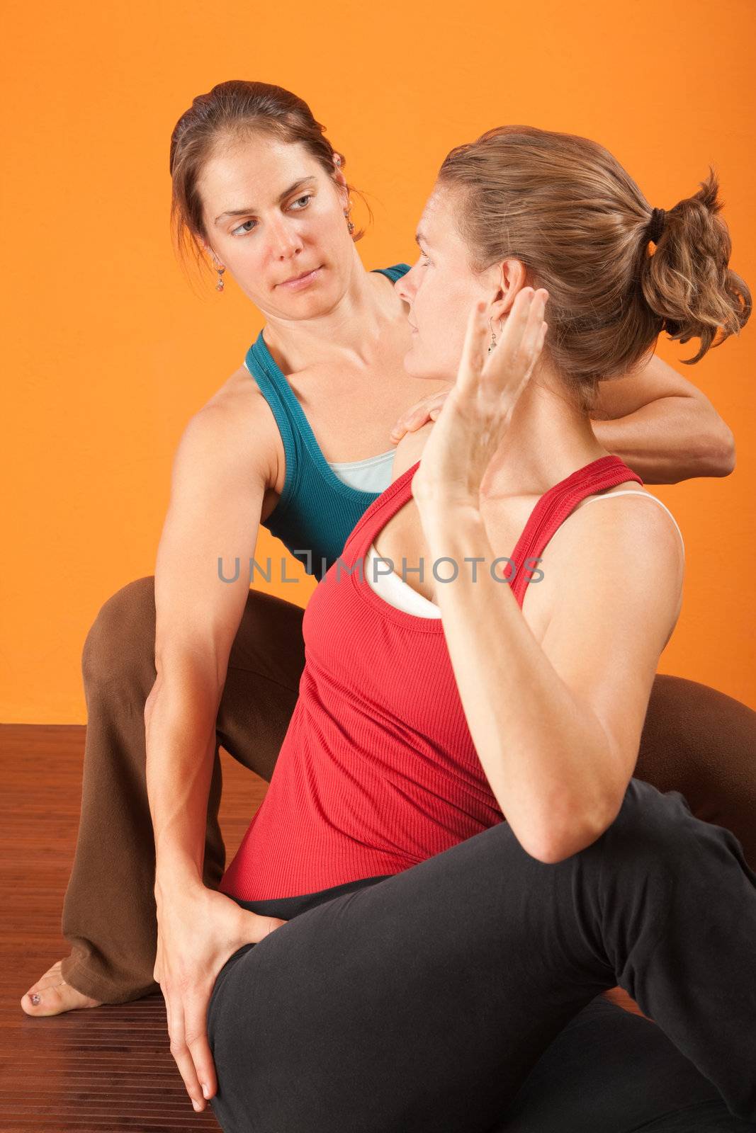 Yogasana coach with student stretching over orange background