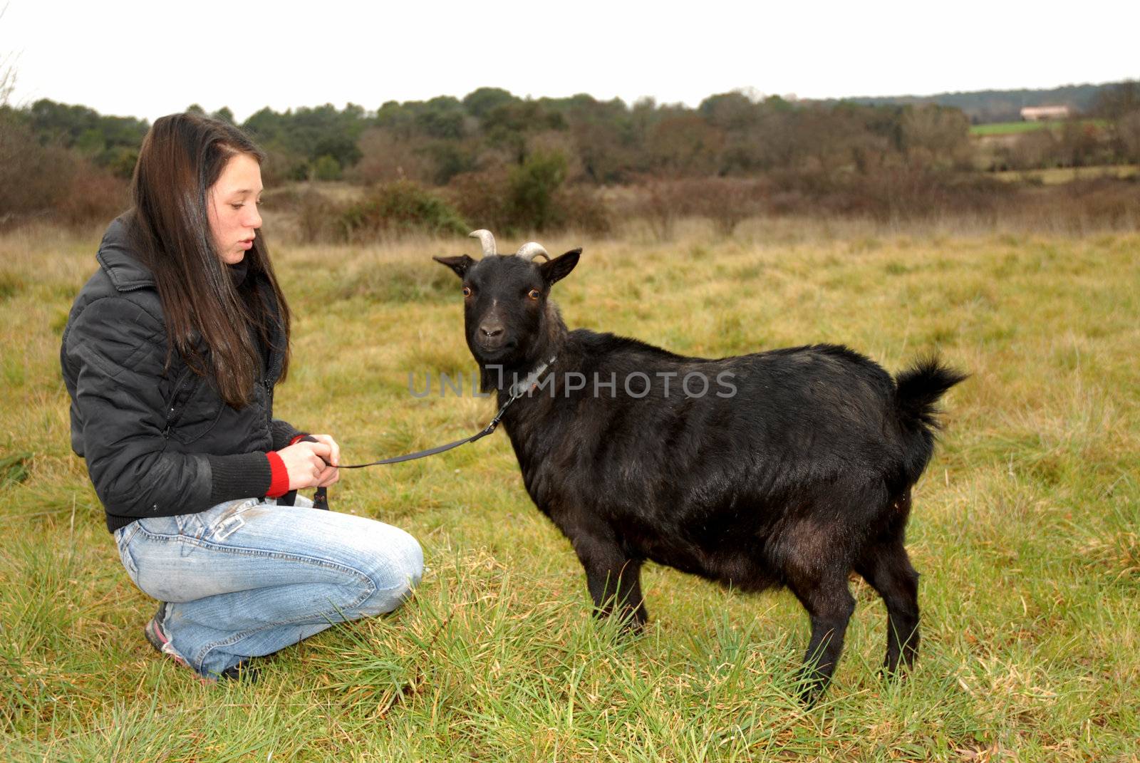 young teenager and a black miniature goat in a field