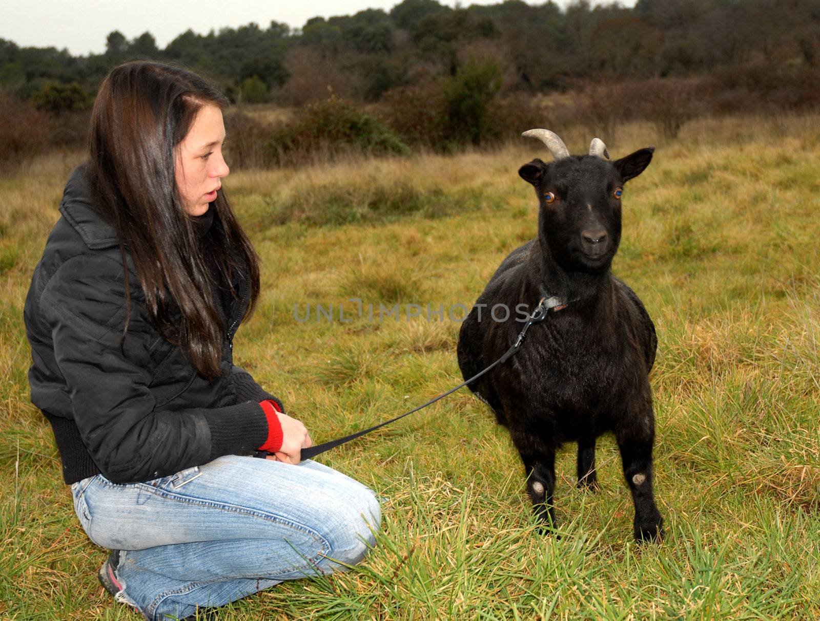 young teenager and a black miniature goat in a field