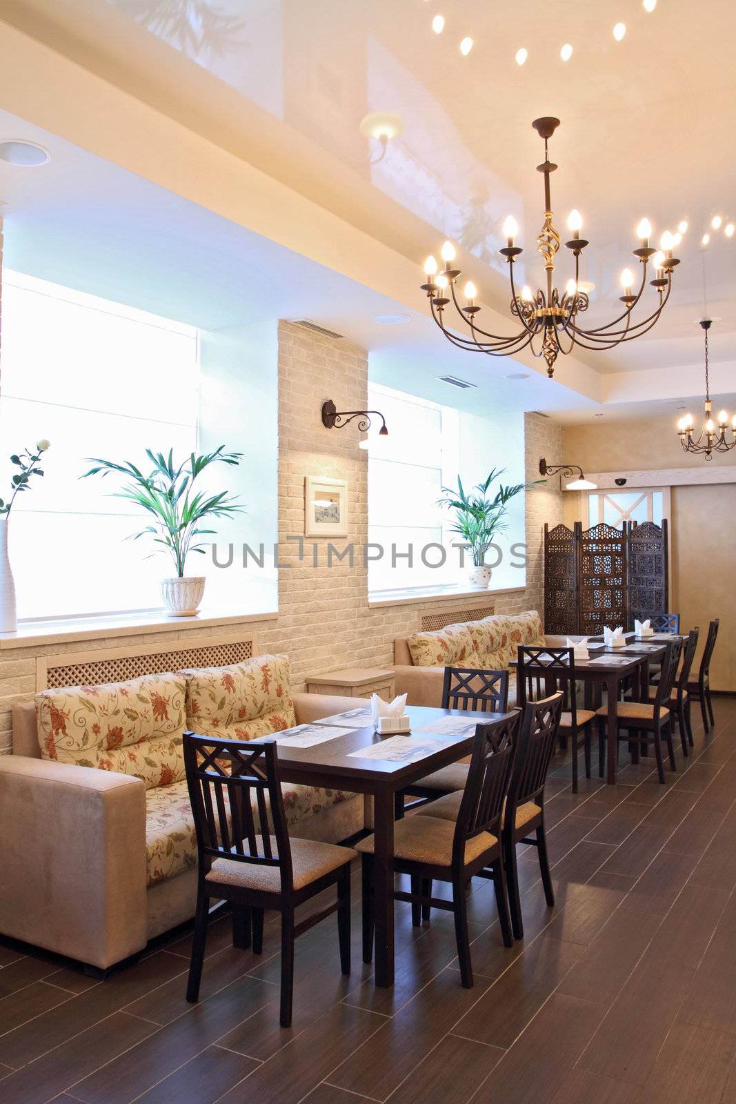 Interior of beautiful modern restaurant with a kind on a number of little tables and a window, a vertical shot