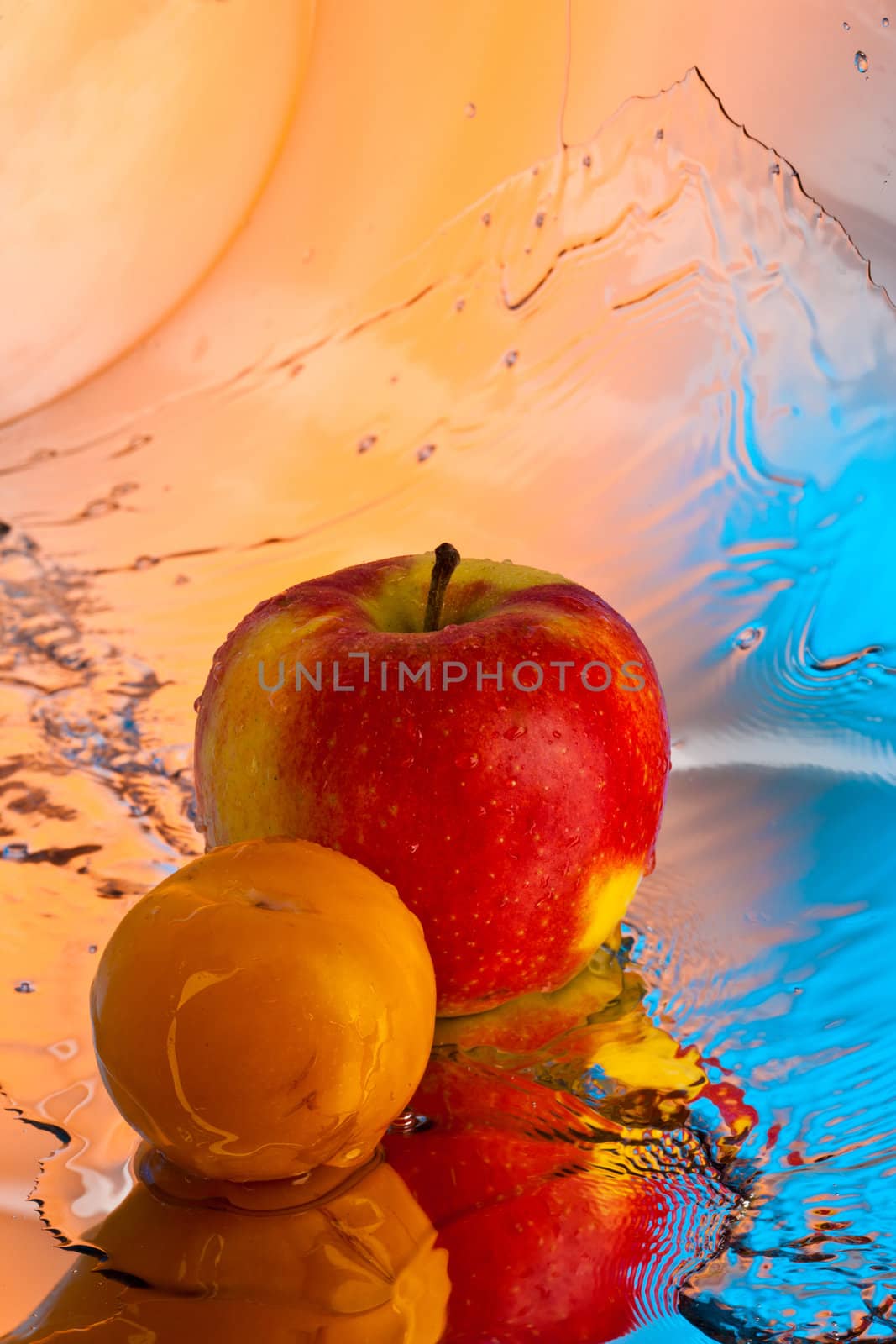 ripe red apple and yellow plum over pink and blue background