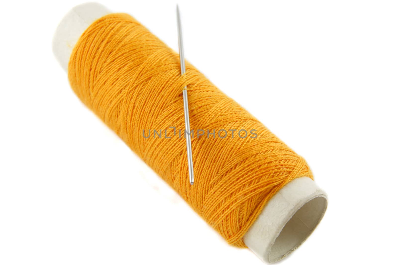 Orange thread bobbin with needle on white background