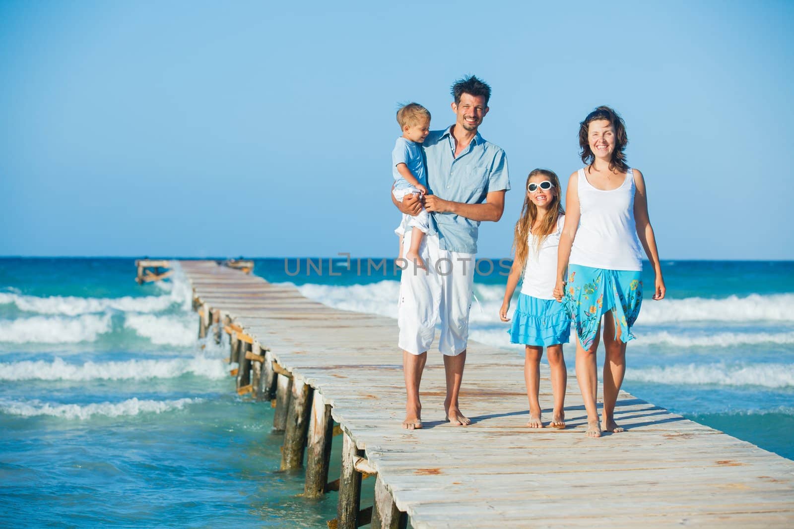 Family of four on jetty by the ocean by maxoliki