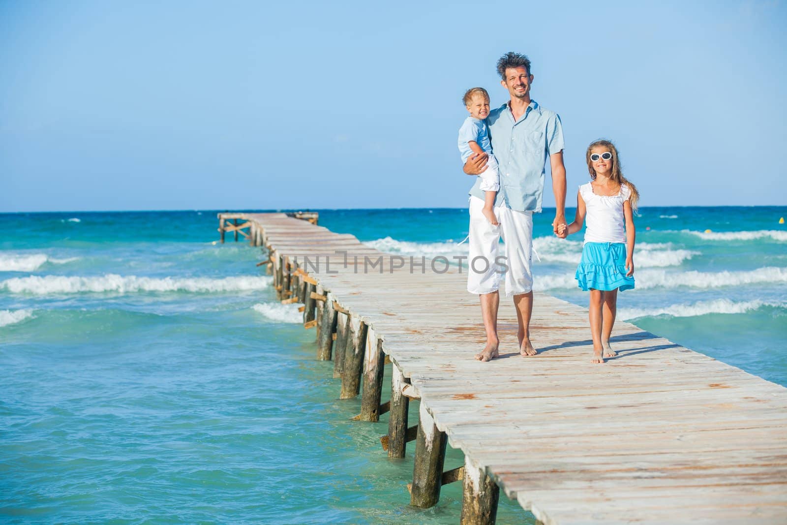 Family of three on wooden jetty by the ocean