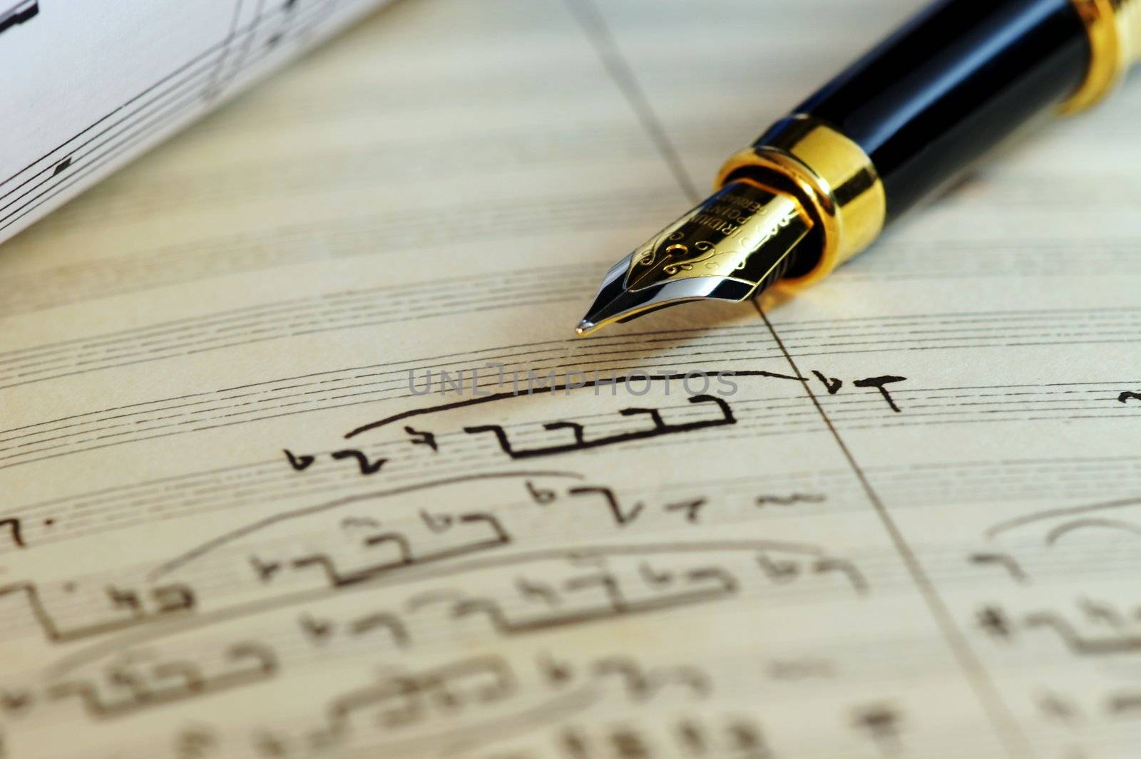 Selective focus of a fountain pen on top of an old sheet music handwritten