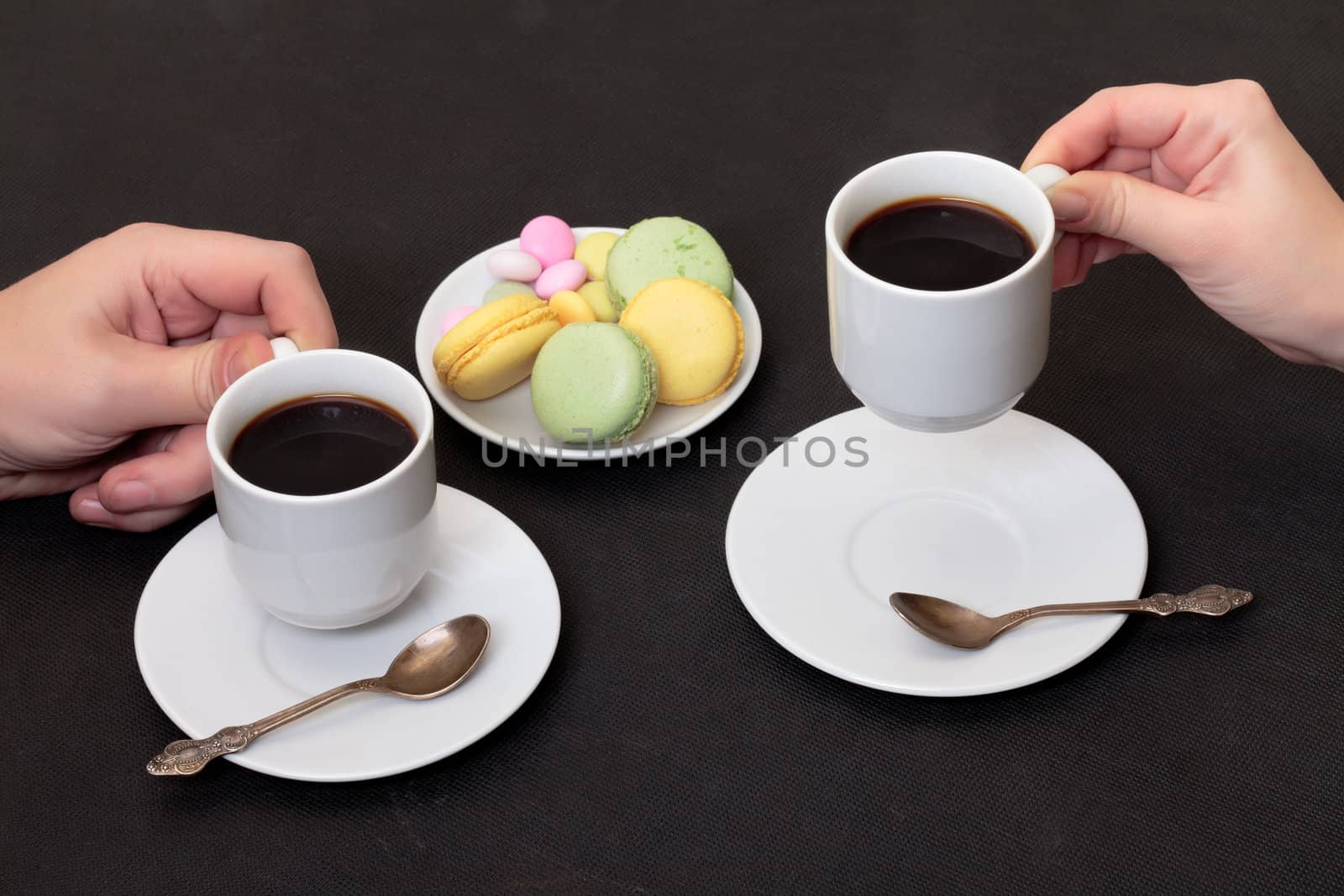 Couple drinking coffee with macaroon, on black