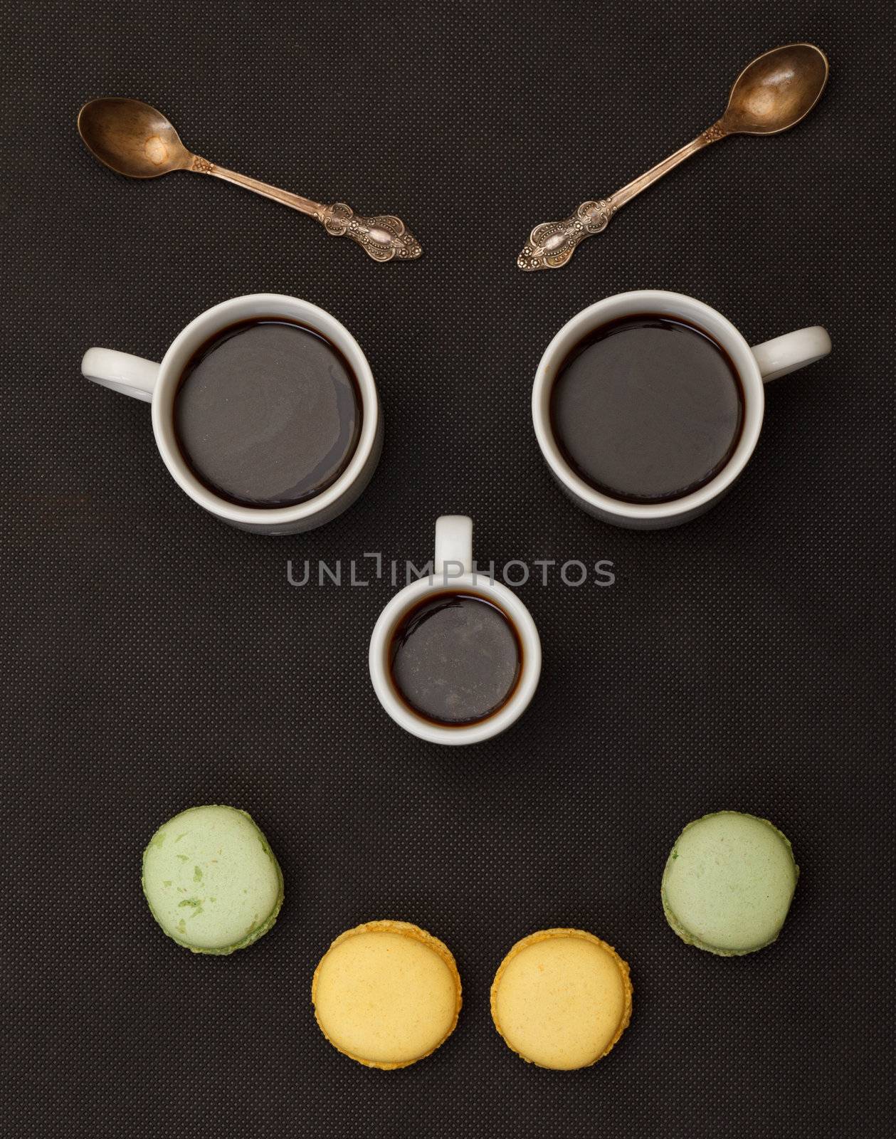 Tree cups coffee and macaroon arranged in happy face by Discovod