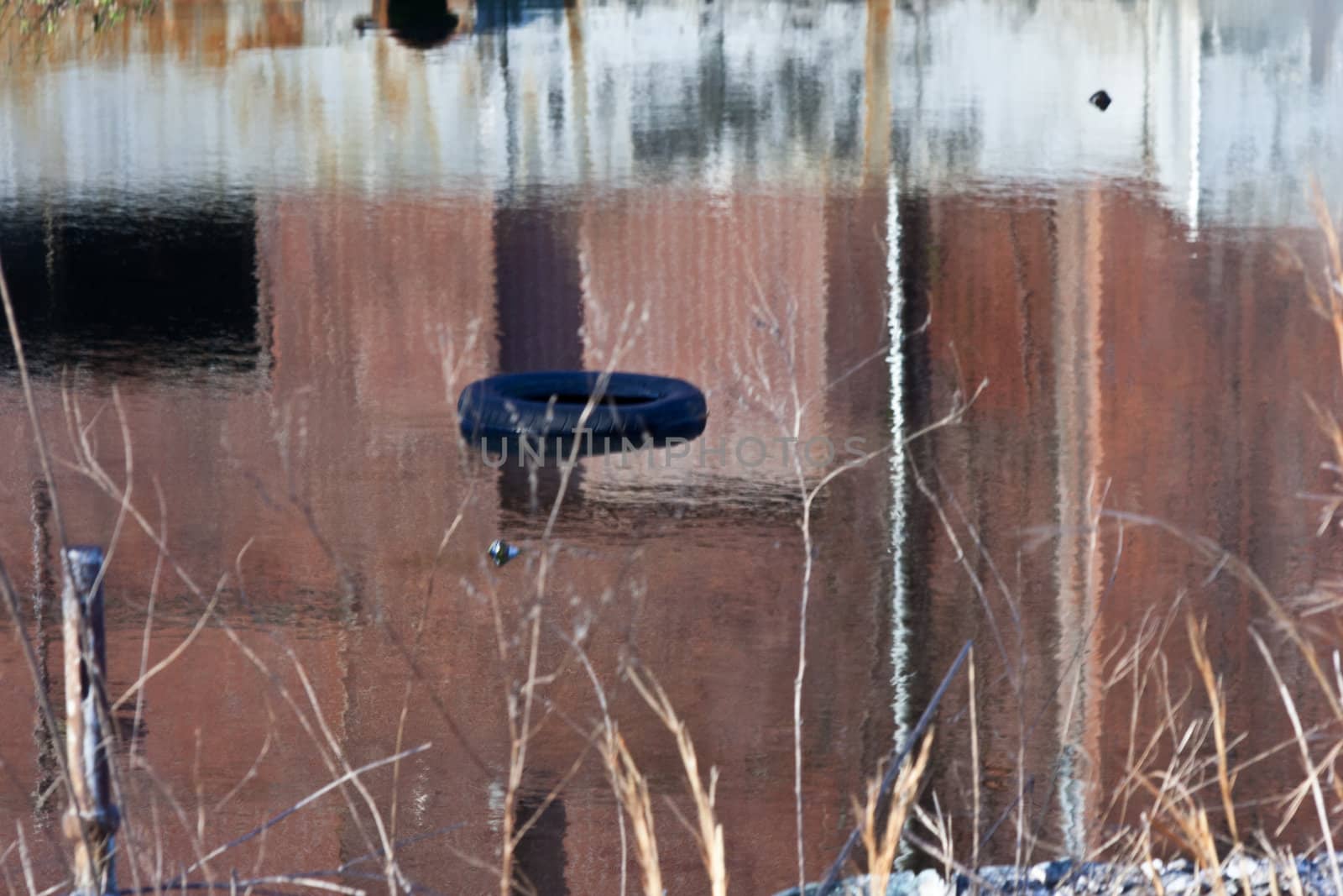 An old tire floating in a pool of water used in a mill operation.