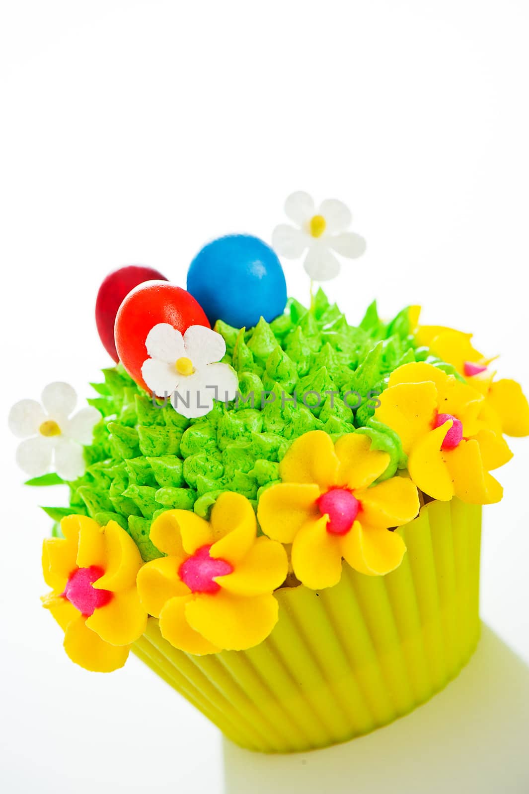 Happy easter cupcake with chocolate egg and cream grass as a meadow with flowers on white background